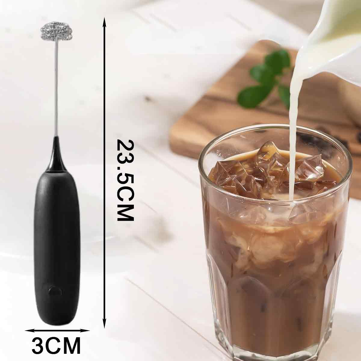 Ein Milchaufschäumer und ein Glas mit Eis und Kaffee. Milch wird in das Glas gegossen. Im Hintergrund ein Holzschneidebrett.