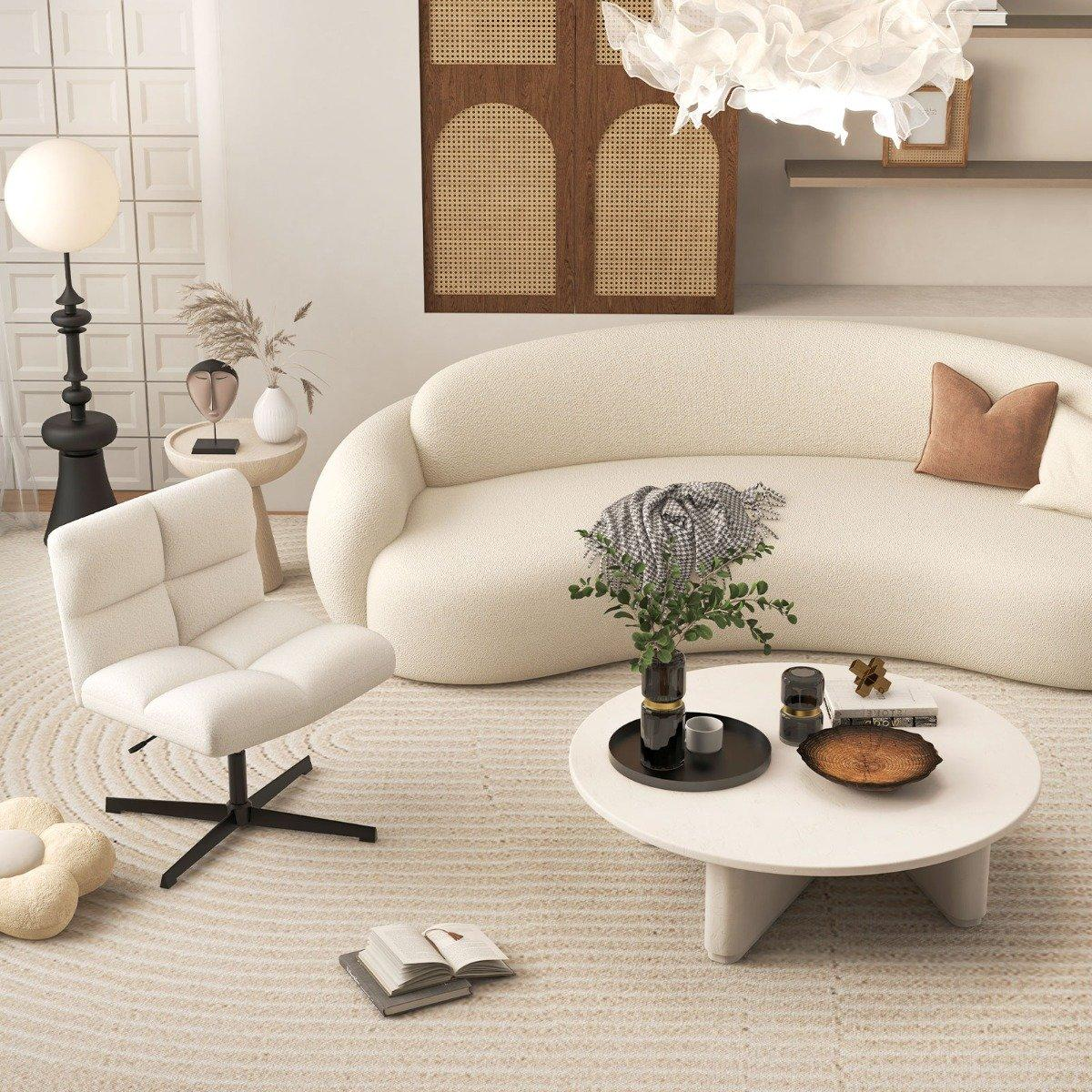 Salón moderno con sofá crema, silla blanca y mesa de centro redonda. Hay una lámpara grande y objetos decorativos.