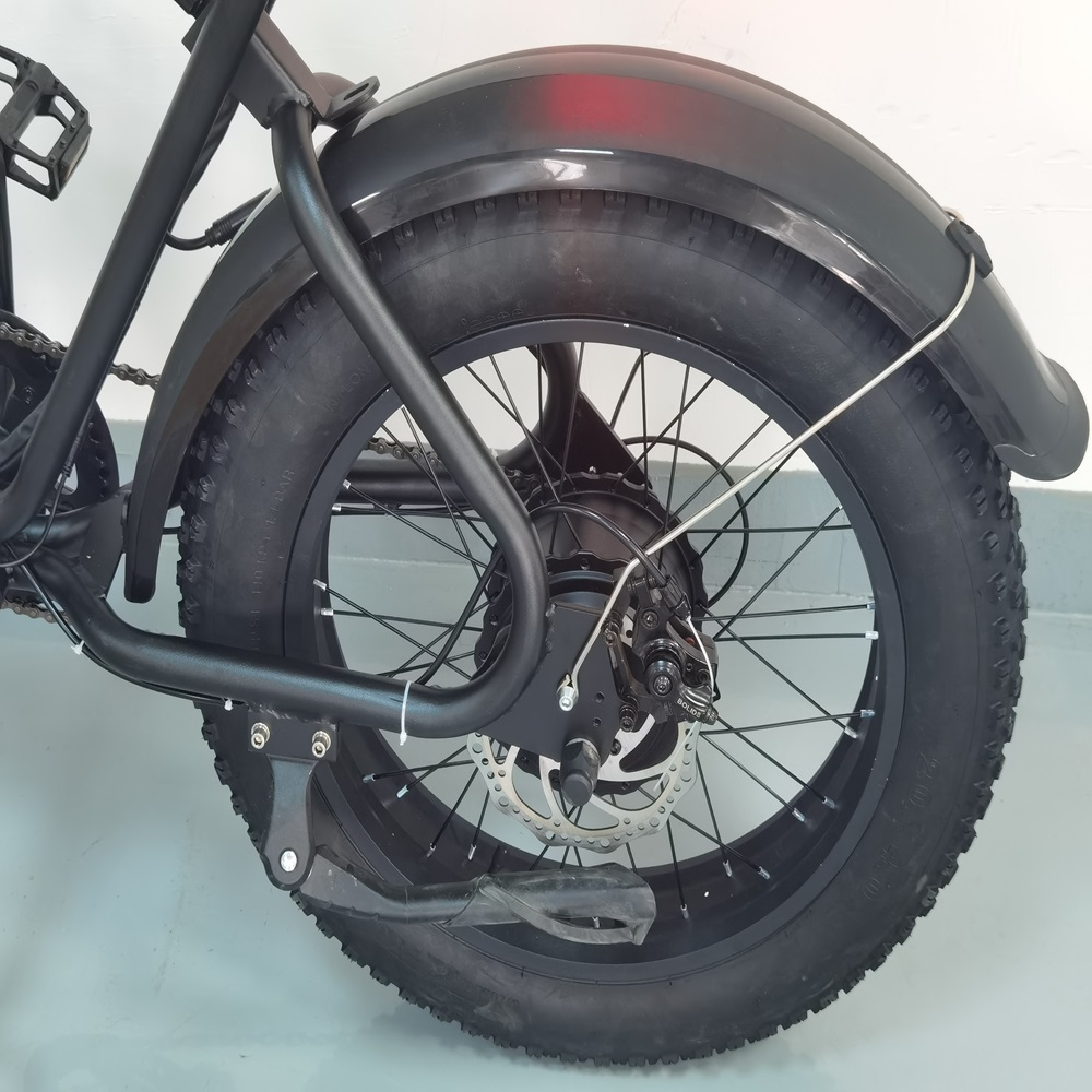 Primo piano di una ruota nera di bici fat. Pneumatico, parafango e telaio sono neri. Si vedono il freno a disco e i raggi.