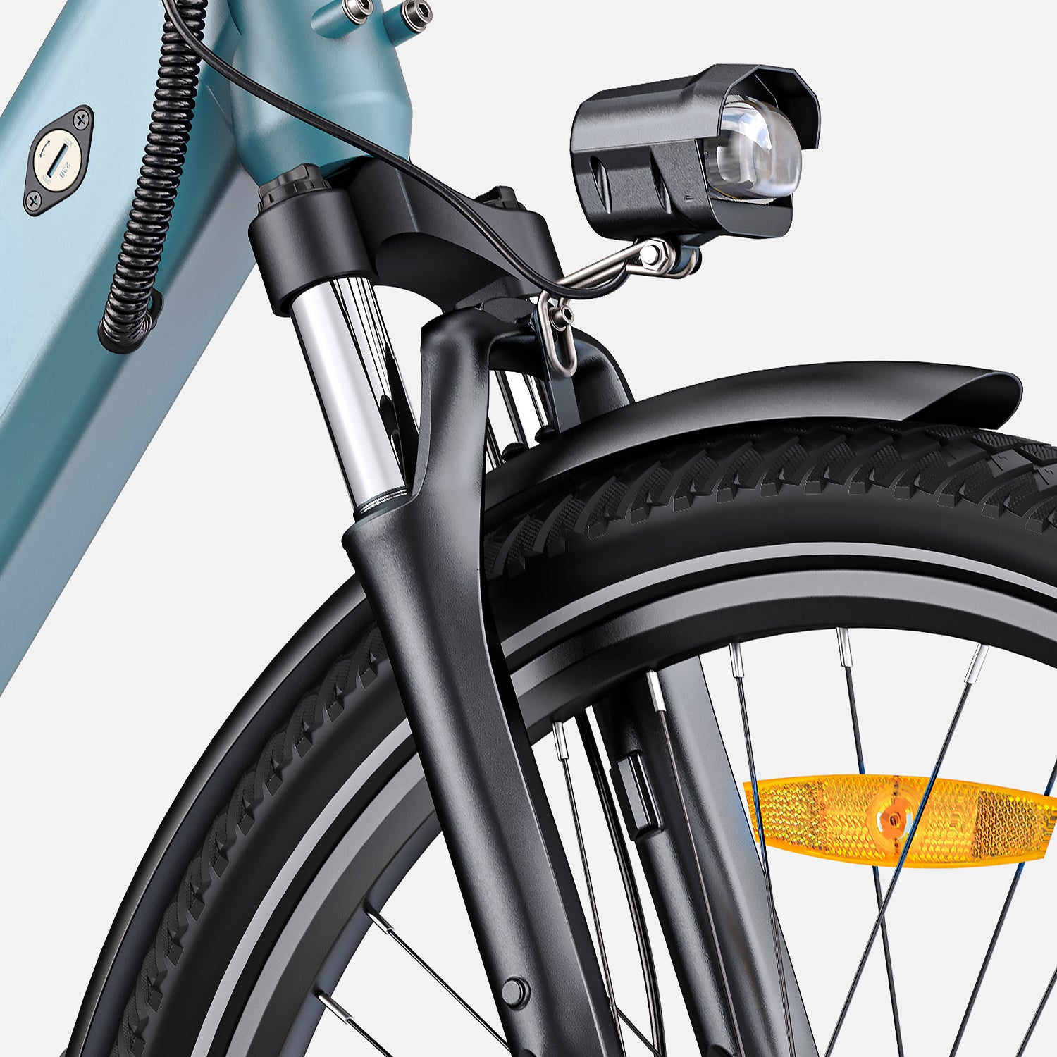 Primer plano de la parte delantera de una bicicleta. Incluye neumático, horquilla, luz, reflector y parte del cuadro. Colores: negro, plata y verde azulado.