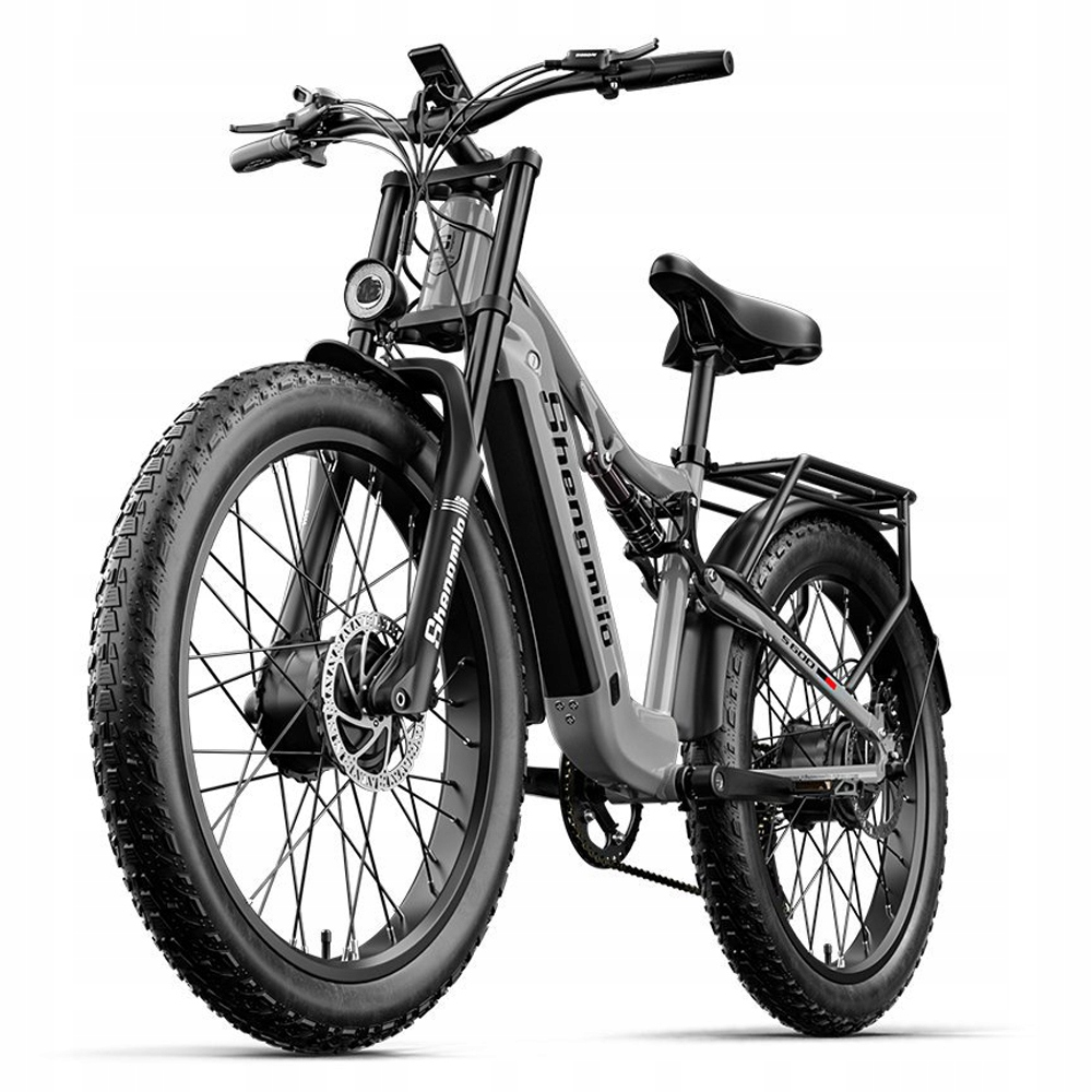 Una bicicletta elettrica grigia e nera è centrata. Ha pneumatici larghi, sella nera e portapacchi.