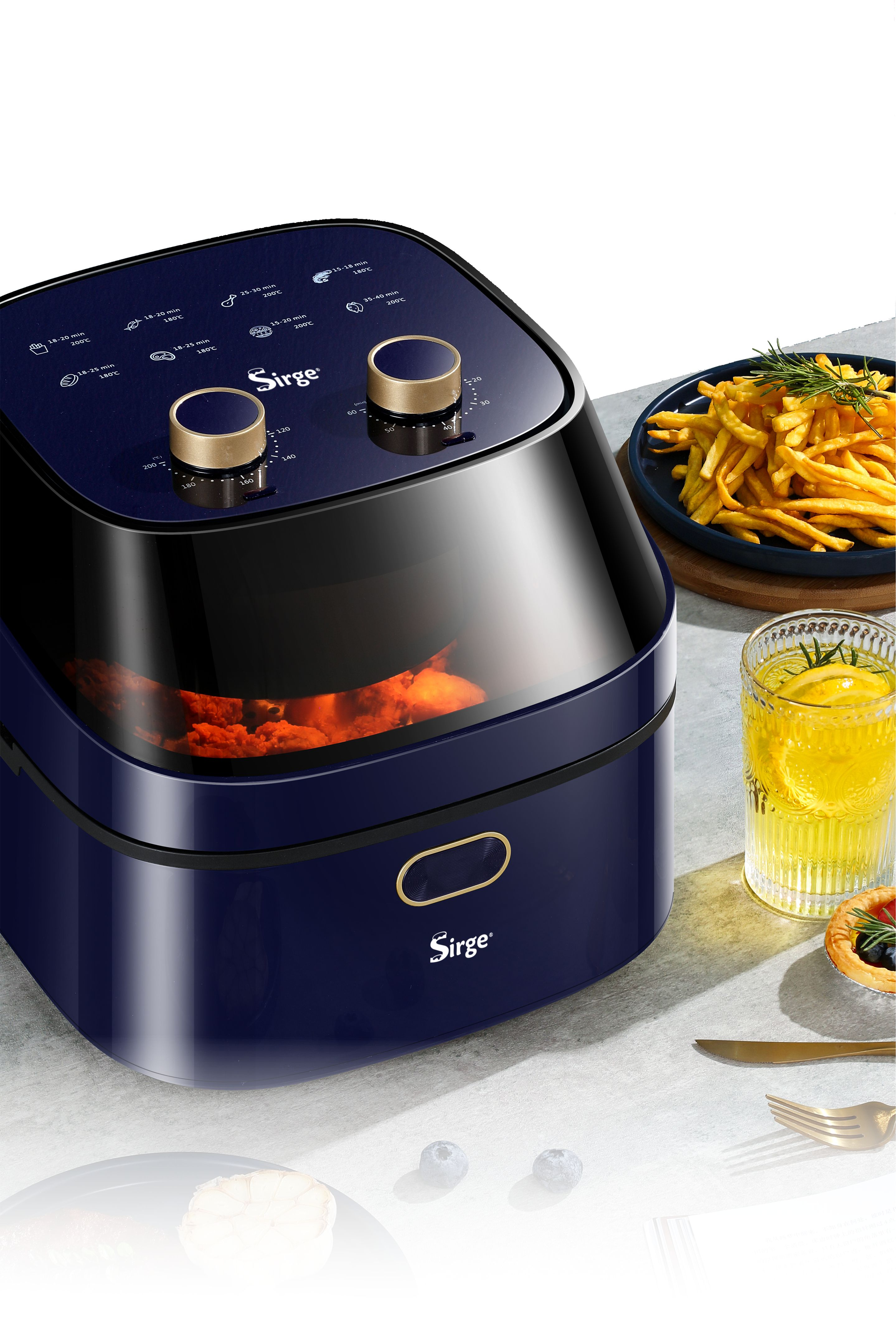 Una friggitrice ad aria blu navy con accenti dorati. Patatine fritte, bevanda al limone e una crostata sono accanto.