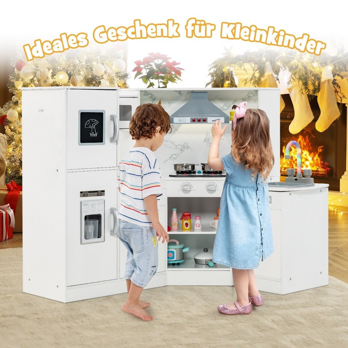 Dos niños juegan con una cocina de juguete blanca. Un niño con una camisa a rayas y una niña con un vestido azul. La cocina tiene nevera, estufa y fregadero.