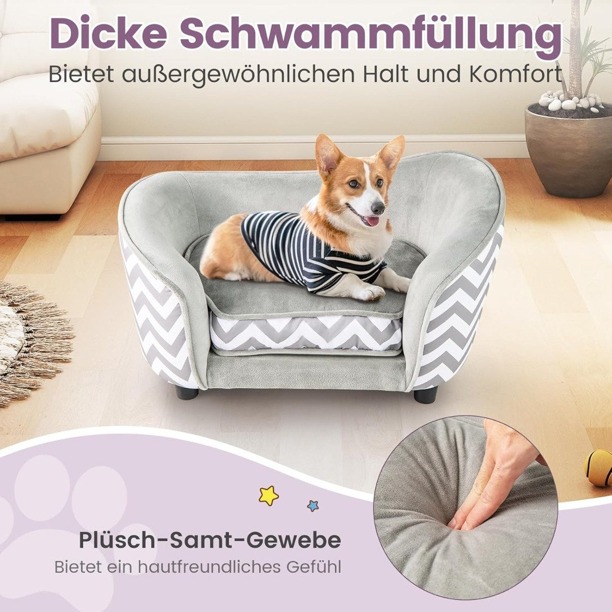 Un corgi con una camisa a rayas yace en una cama para perros. La cama es gris con un patrón de chevrón. Una mano presiona la tela de felpa de la cama.