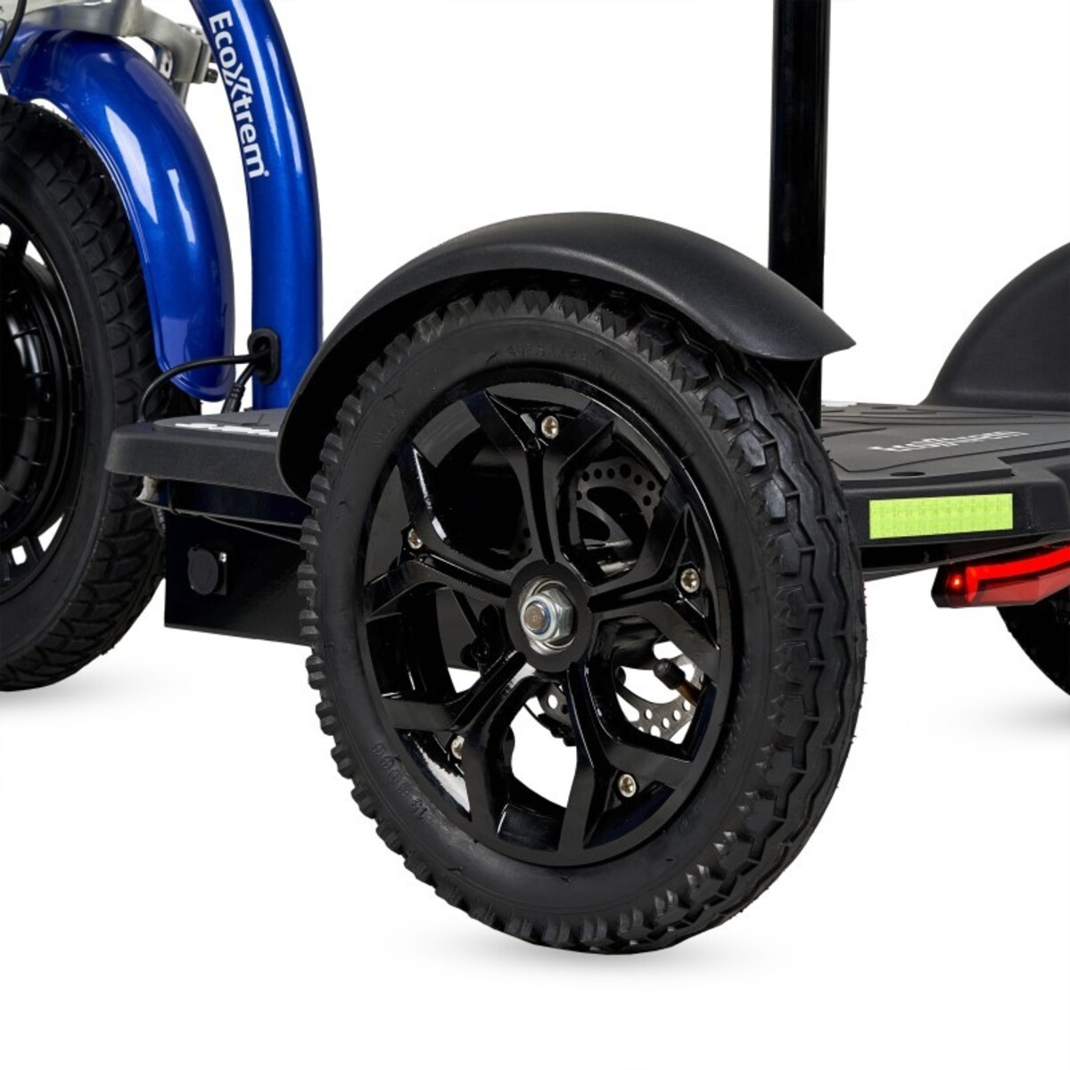 Primer plano de un scooter de movilidad azul y negro. Muestra ruedas, guardabarros y la marca Ecoxtrem. Los neumáticos tienen dibujo.