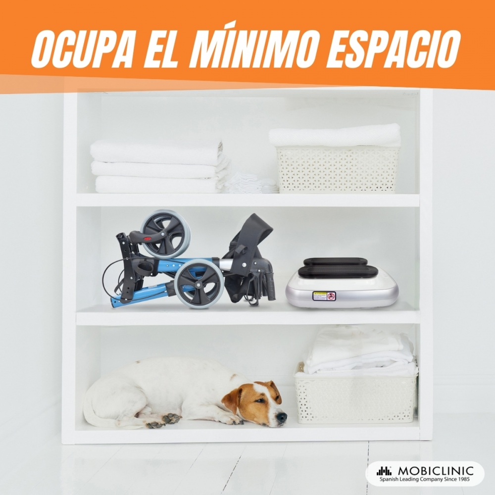Un armario blanco con estantes. Andador plegado, toallas, plataforma vibratoria y perro descansando. Texto: 'OCCUPA EL MÍNIMO ESPACIO'.
