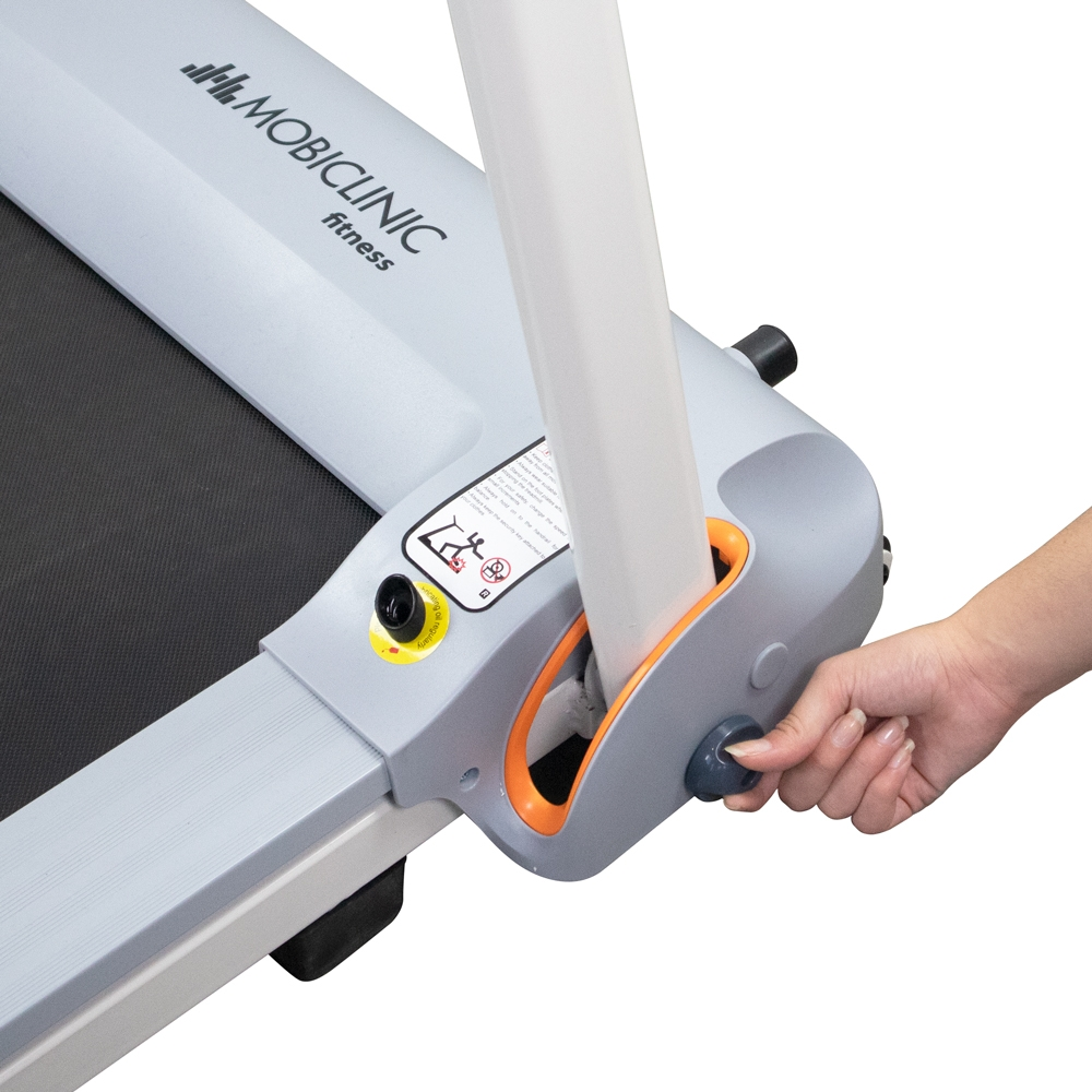 Una mano ajusta un control de cinta de correr. La cinta es gris y blanca, con detalles en naranja. La marca es visible.