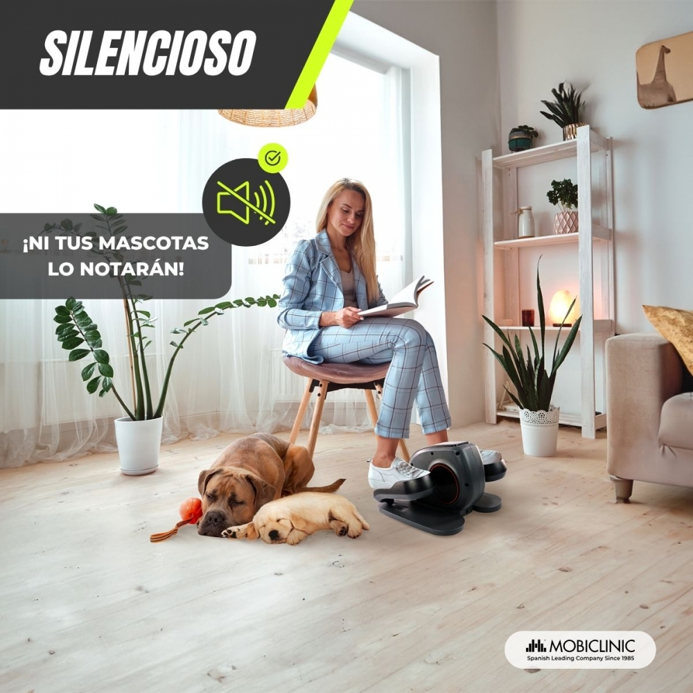 Mujer con traje azul lee. Dos perros yacen en el suelo. También se ve una elíptica y plantas. El texto dice 'Silencioso'.