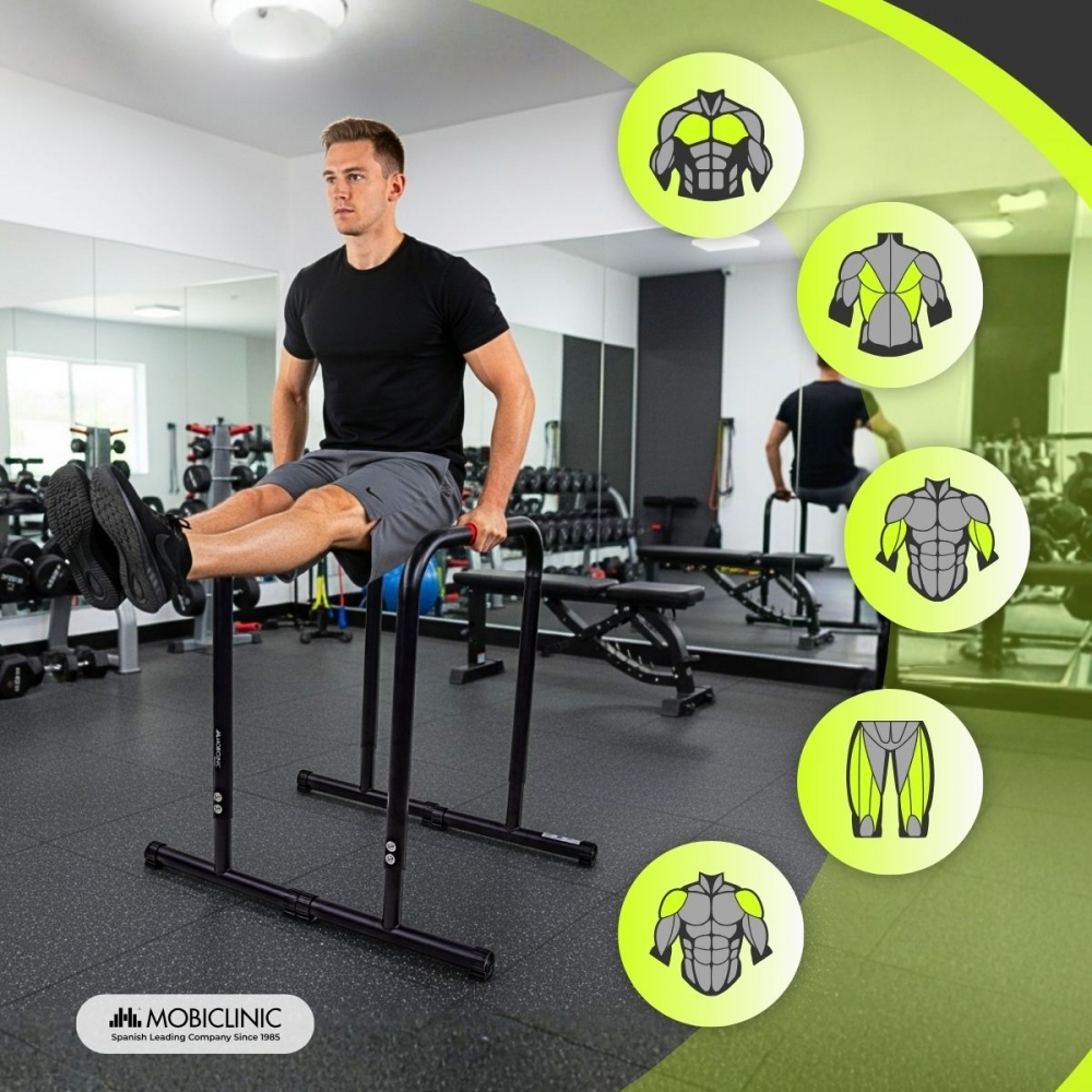 Un hombre haciendo un ejercicio de flexiones en barras paralelas en un gimnasio. Otras personas están haciendo ejercicio, junto con equipos de entrenamiento.