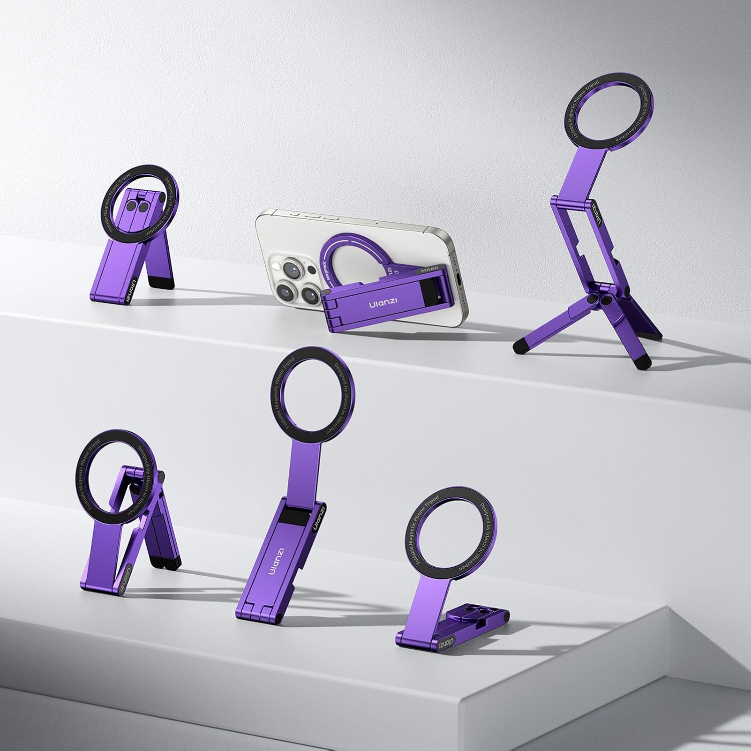 Sono esposti diversi supporti per telefono viola con anelli neri. Uno tiene un telefono. I supporti presentano il marchio "Ulanzi".