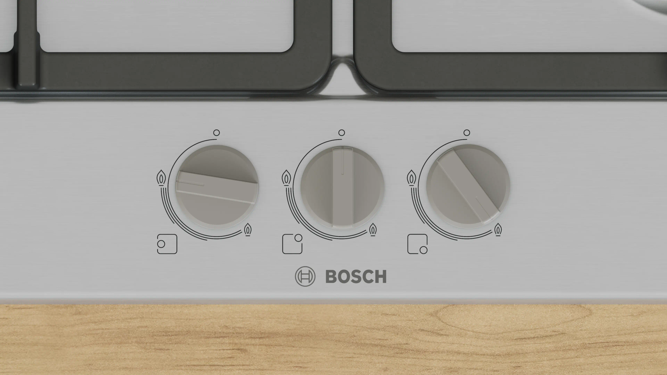 Zbliżenie panelu sterowania kuchenki Bosch z trzema pokrętłami, ikonami płomieni i drewnianą powierzchnią.