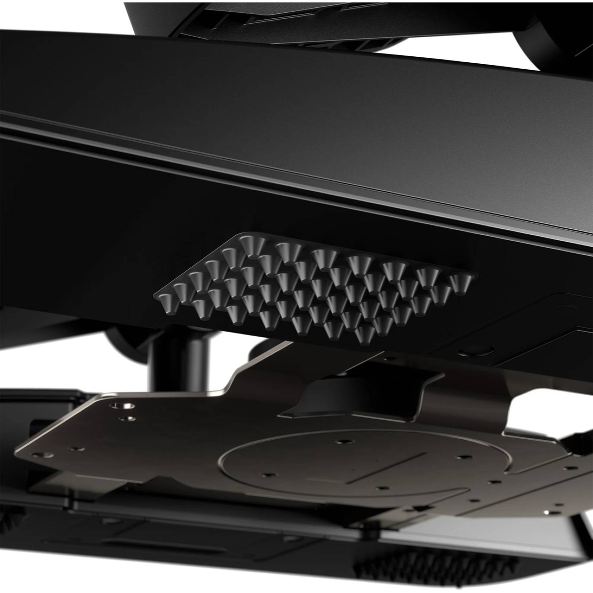 Vista de cerca de un soporte de monitor negro. Una cuadrícula de pequeños pernos grises en forma de cono está adherida al soporte. Varias piezas de metal son visibles.