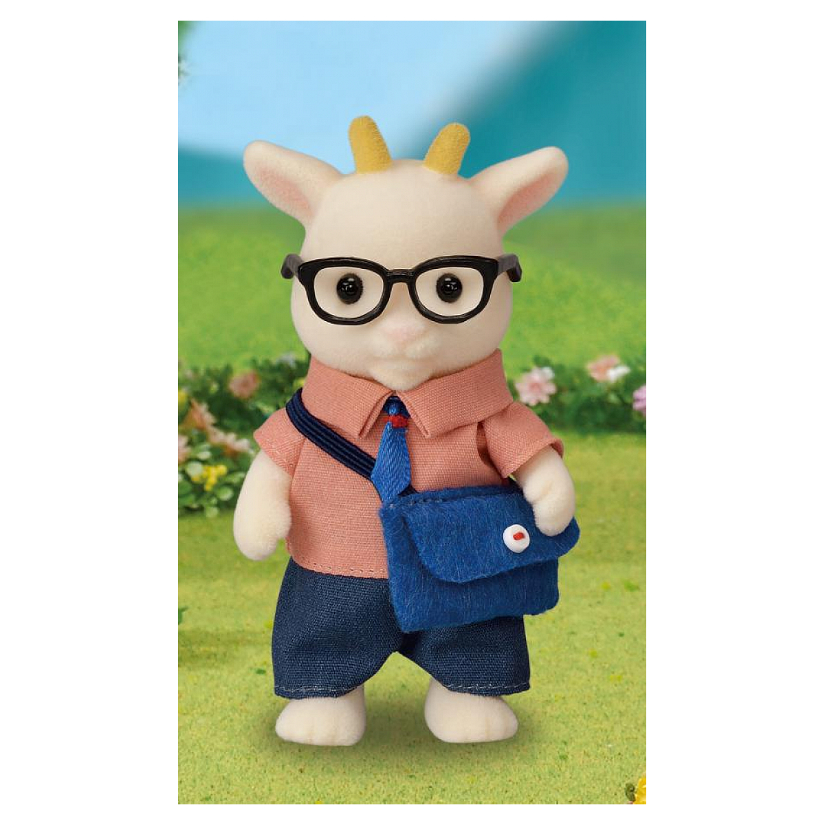 Un juguete de cabra con gafas, camisa rosa, pantalones cortos azules y una bolsa azul. Está sobre hierba con fondo verde y flores.