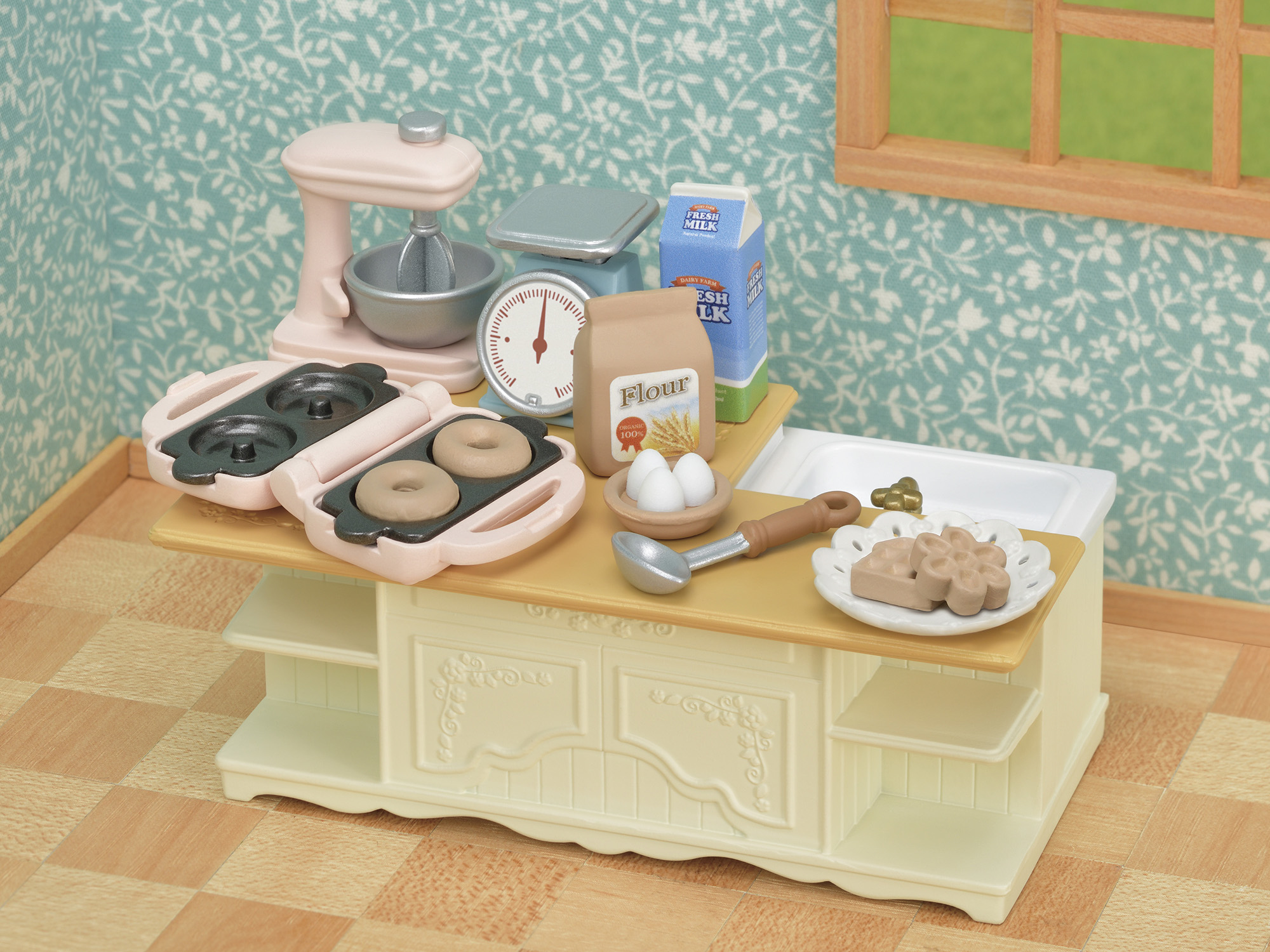 Una escena de cocina en miniatura con utensilios para hornear: batidora, balanza, harina, leche, donuts, huevos y pasteles.
