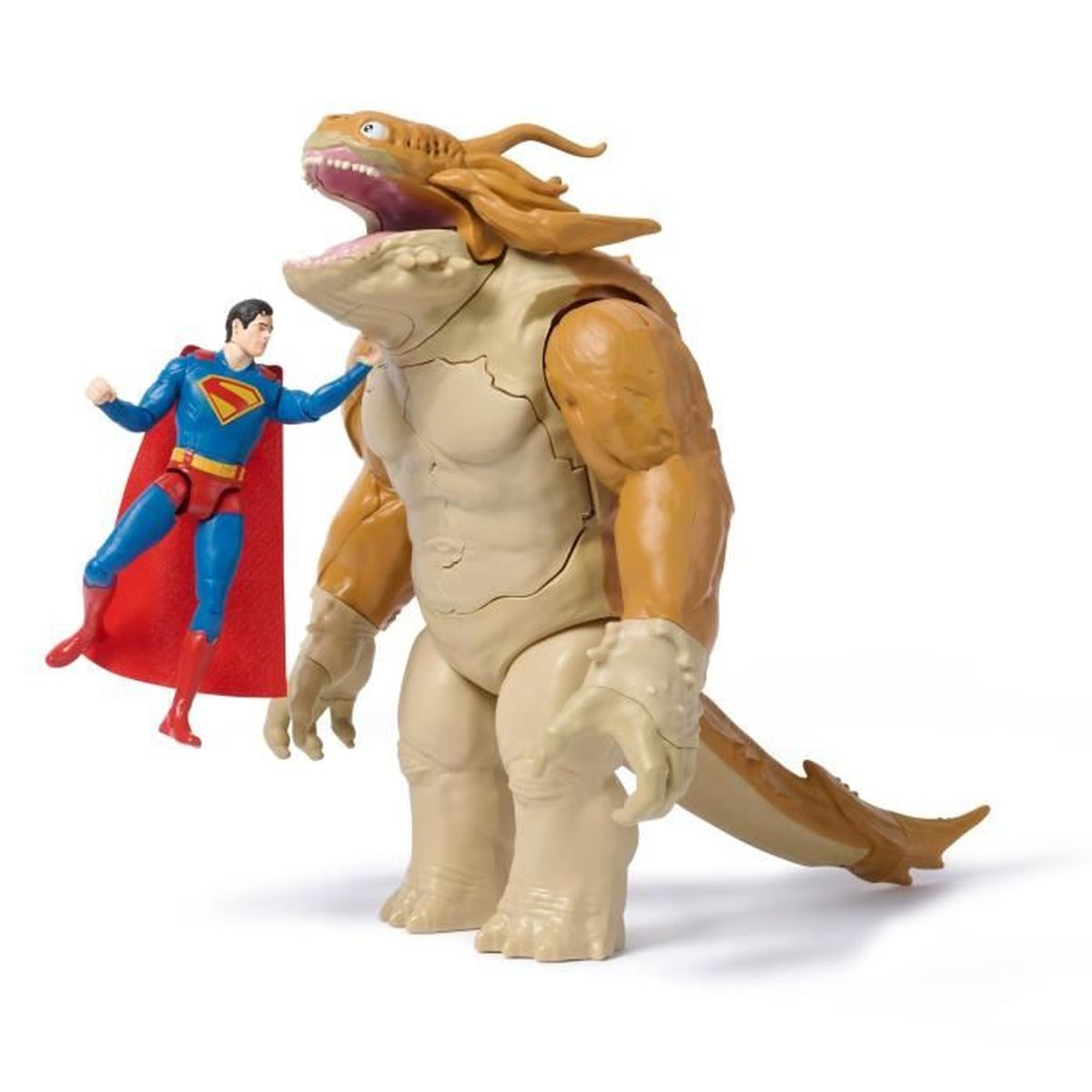 Figura de Superman en vuelo enfrentándose a un gran juguete monstruo. El monstruo es de color beige, marrón y crema, con la boca abierta.