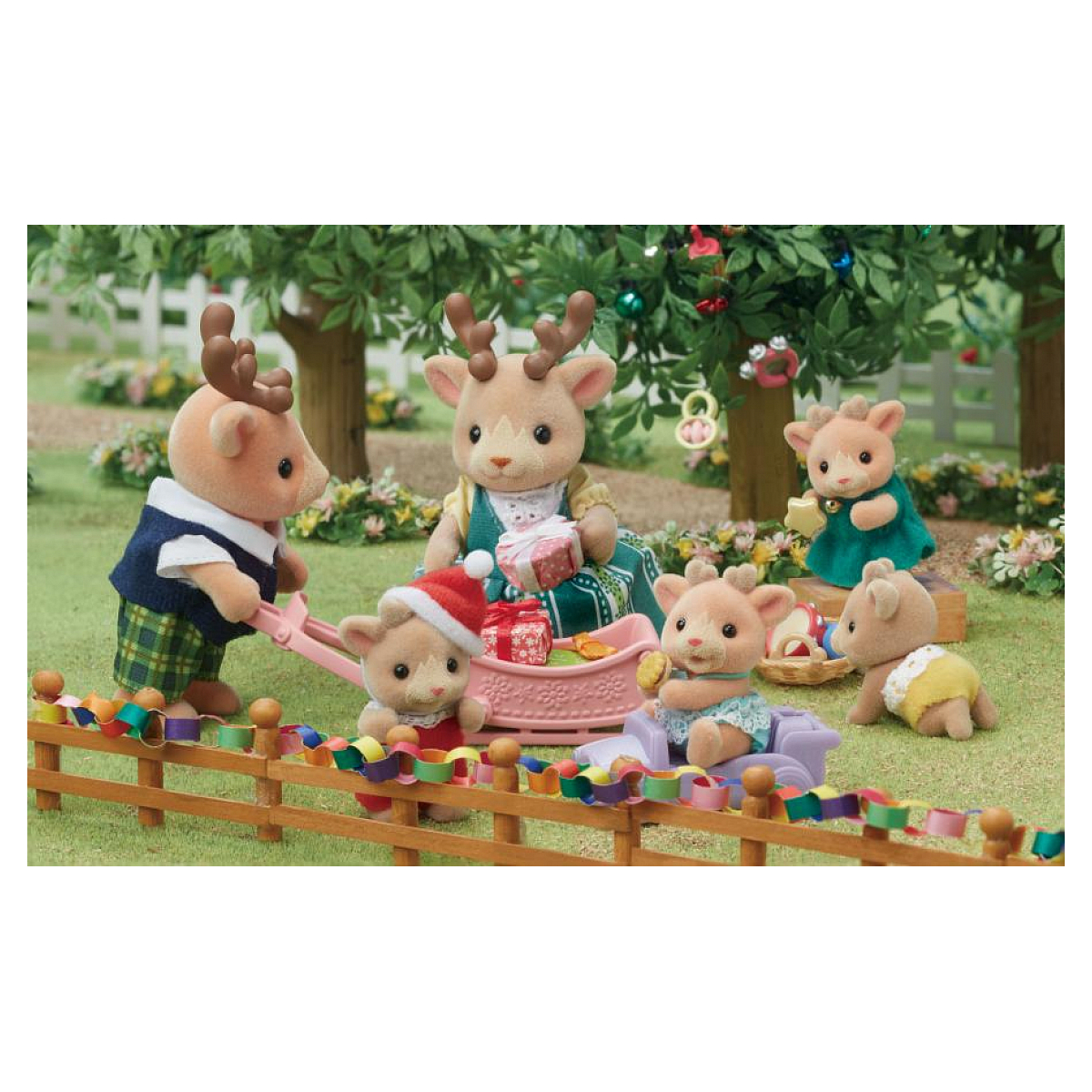 Una familia de renos de juguete está en un jardín. Un reno tira de un carro con regalos. Otros juegan, vistiendo ropa festiva.