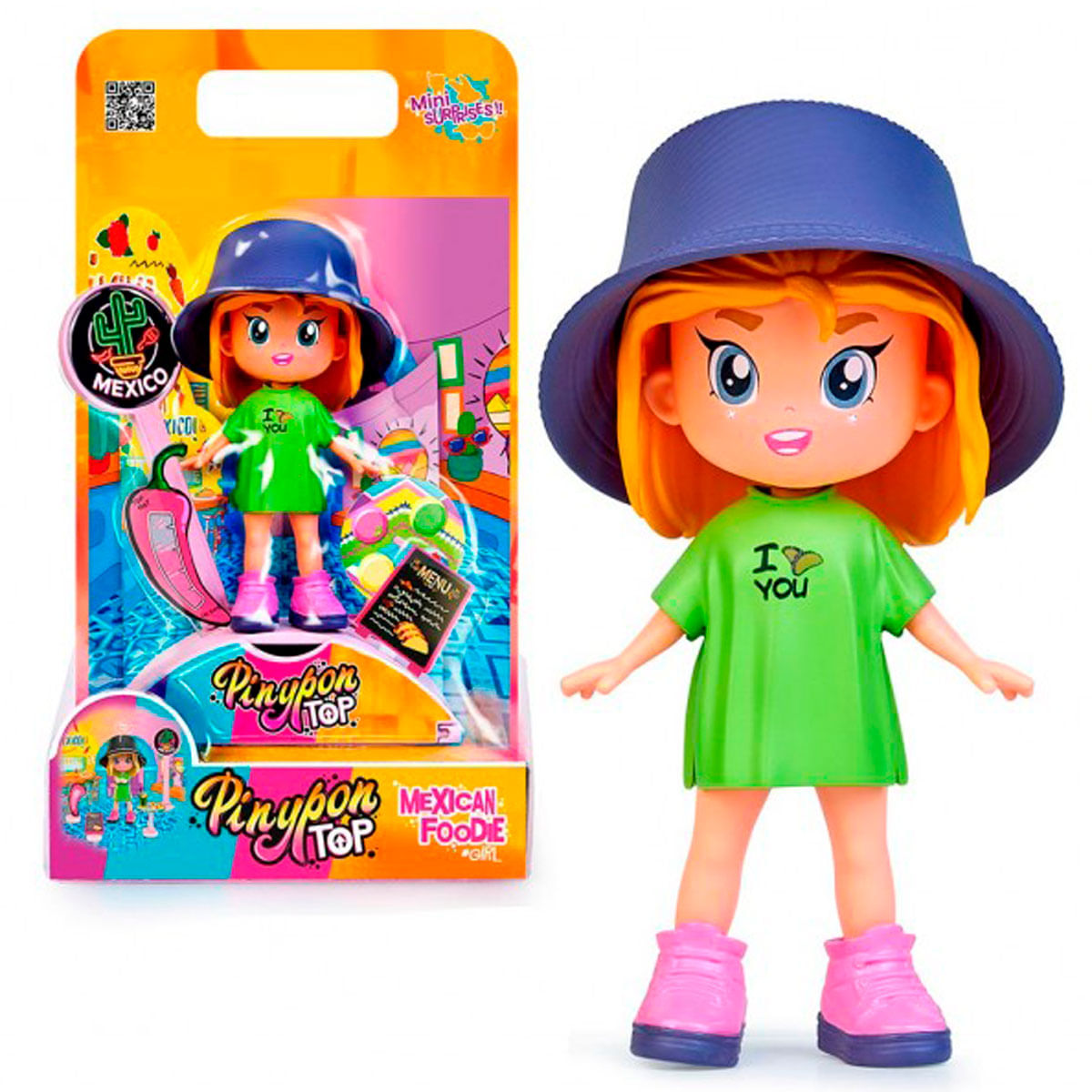 Una muñeca con un vestido verde y un sombrero azul. Tiene pelo naranja y botas rosas. El embalaje muestra la misma muñeca.