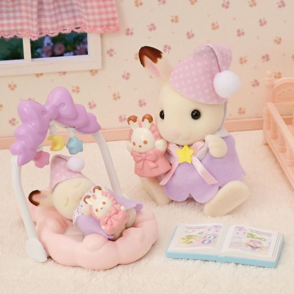 Una escena con dos figuras de conejitos y un bebé en una cuna rosa. Un conejito sostiene un juguete. Un libro y una cuna también están presentes.