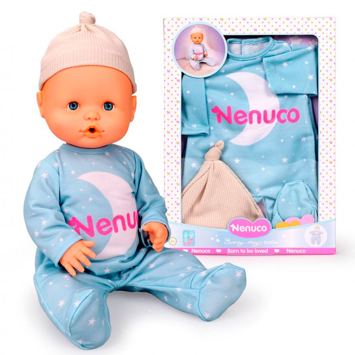 Una muñeca bebé con pijama azul con estampado de luna. Un gorro a juego y la caja del conjunto están al lado.