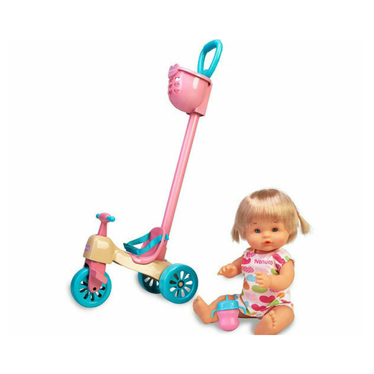 Una muñeca está sentada junto a un triciclo de juguete con un tema rosa y turquesa. Tiene una cesta y un asa. Hay un biberón en el suelo.