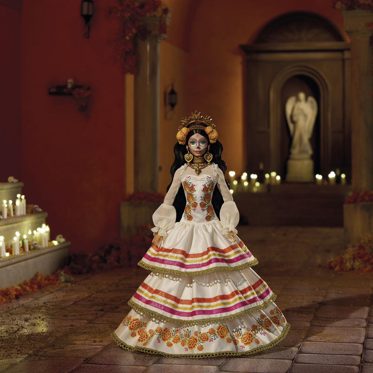 Una muñeca con un vestido blanco con motivos florales y la cara pintada está en una habitación iluminada por velas. La muñeca tiene una corona y está rodeada de velas.