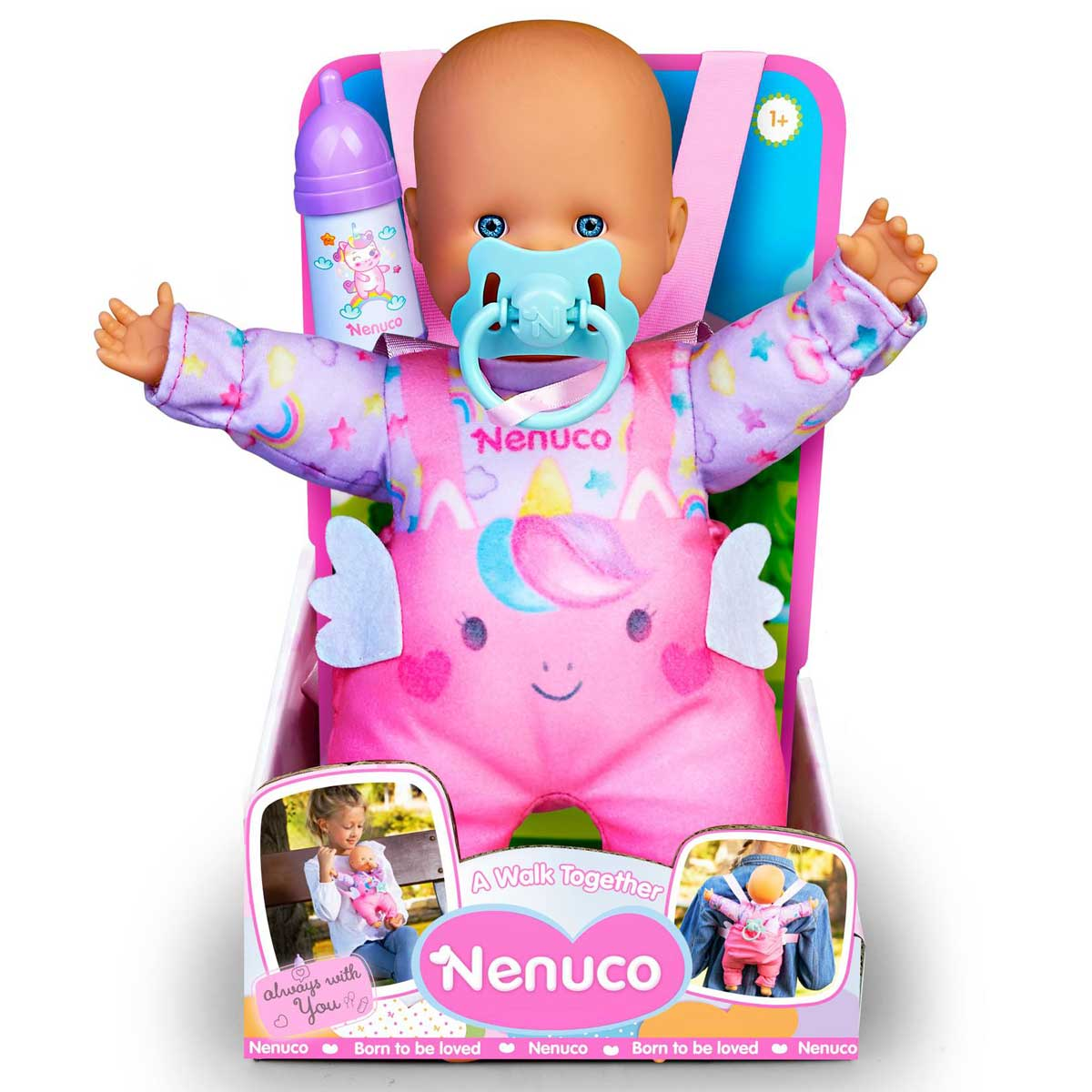 Una muñeca Nenuco con ojos azules y chupete, vestida con un traje de unicornio rosa, está en una caja. Se ve un biberón. La caja tiene 'Nenuco'.