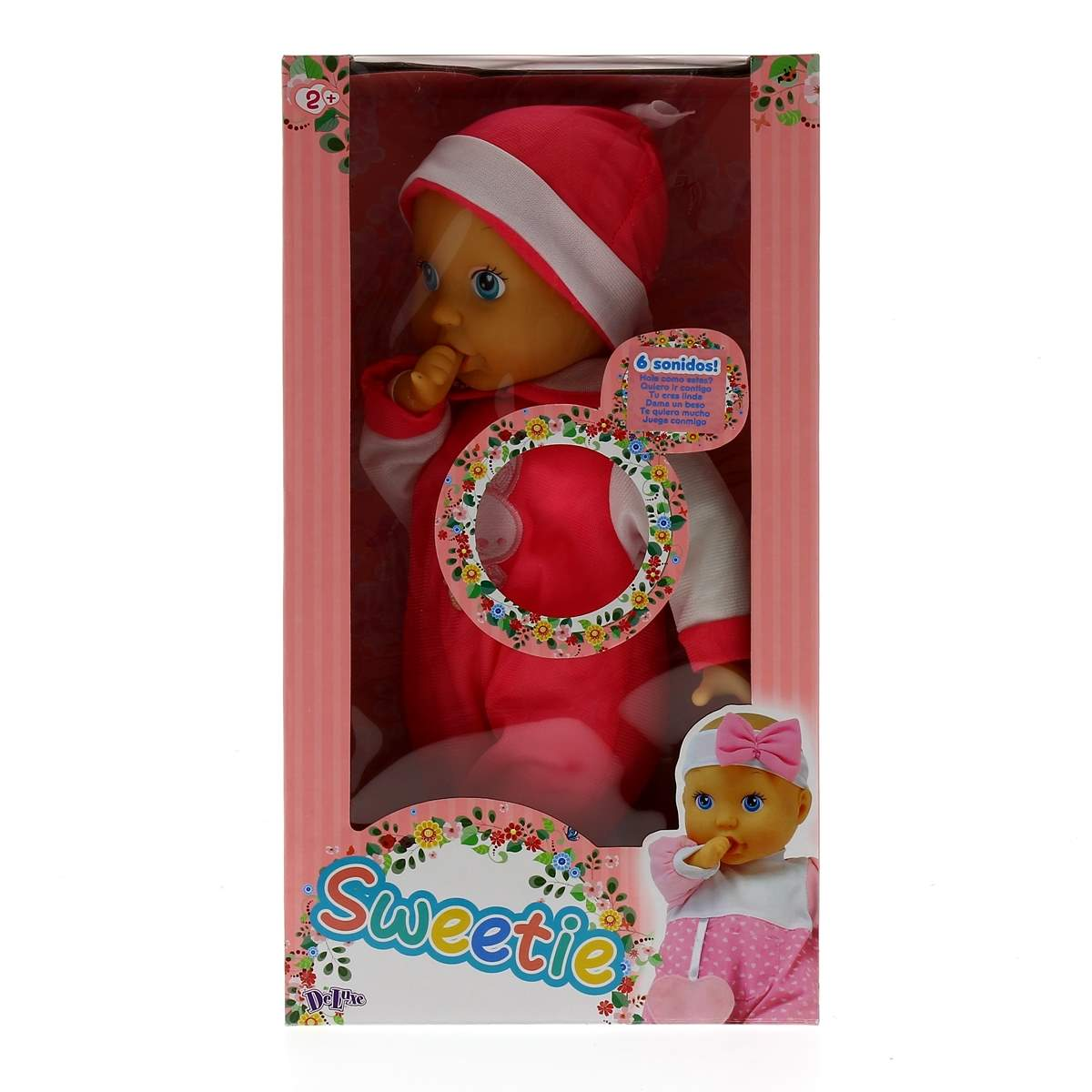 Una muñeca bebé en una caja. Viste un traje rosa, un gorro blanco y tiene ojos azules. La caja dice 'Sweetie'.
