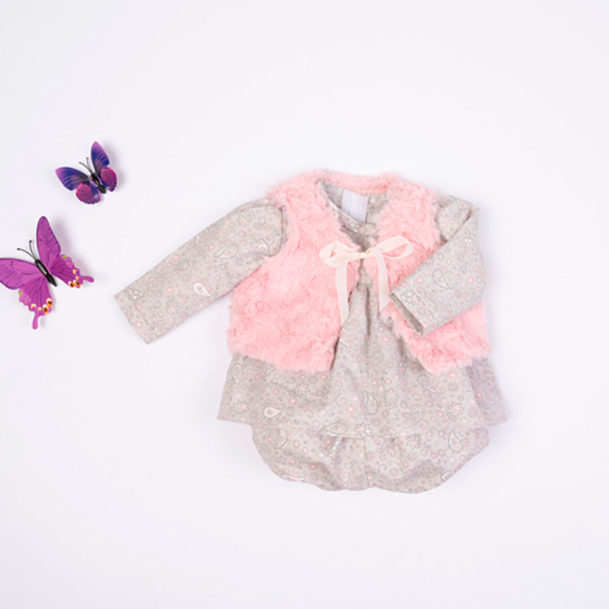 Conjunto de bebé con chaleco de piel rosa y vestido estampado, decorado con dos mariposas sobre fondo blanco.