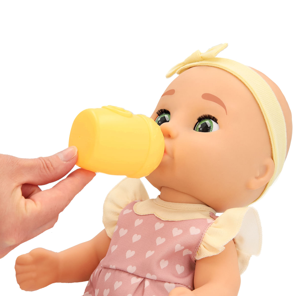 Una muñeca bebe de una botella amarilla. La muñeca lleva un vestido rosa con corazones, una diadema amarilla y tiene ojos verdes.