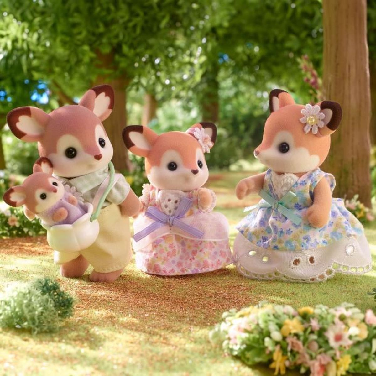 Drei Rehbockfiguren in einem Wald. Einer trägt ein Baby. Andere tragen Kleider. Grünes Gras und Bäume sind im Hintergrund.