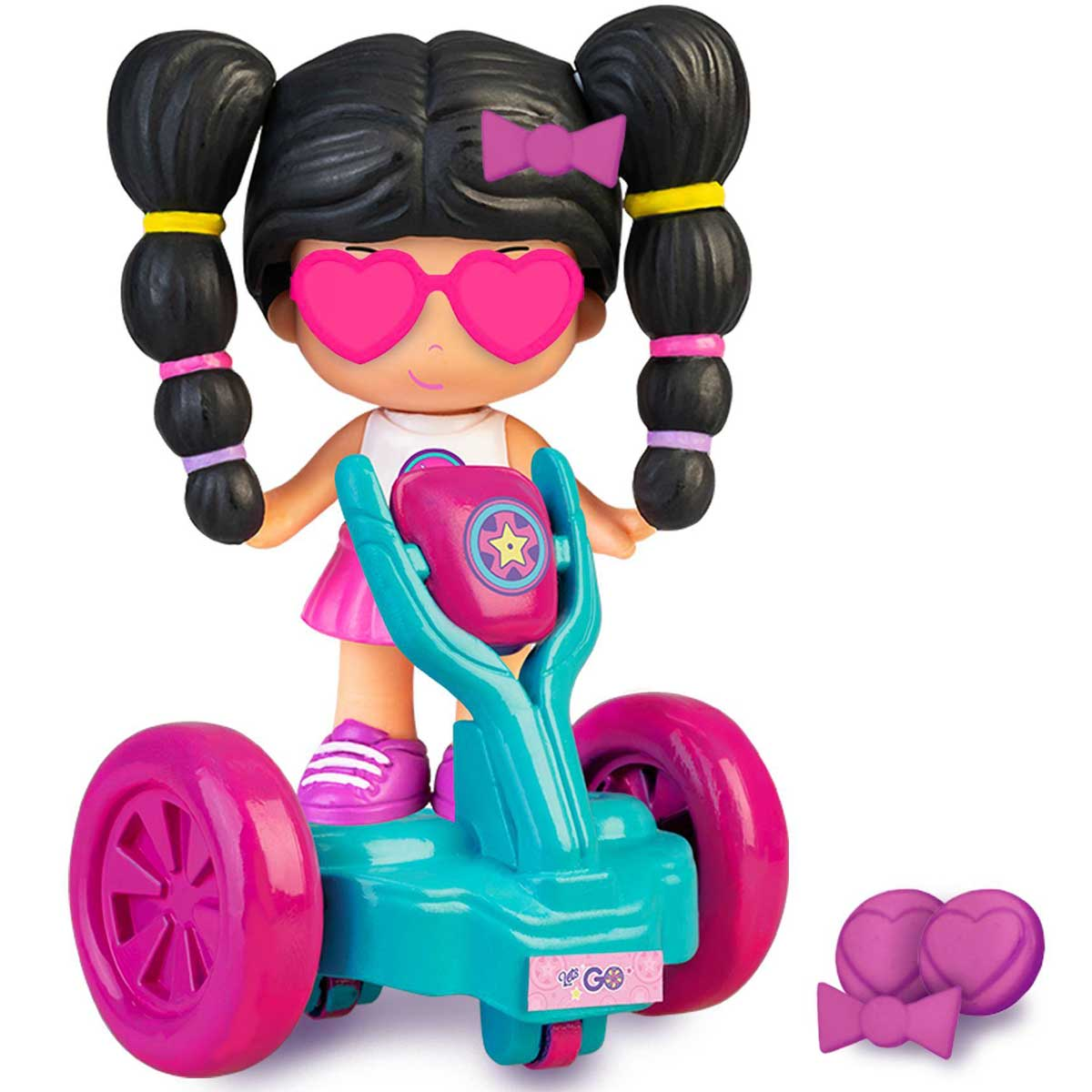 Una muñeca con gafas de corazón monta un patinete. La muñeca tiene coletas y un lazo rosa. El patinete es turquesa y rosa.