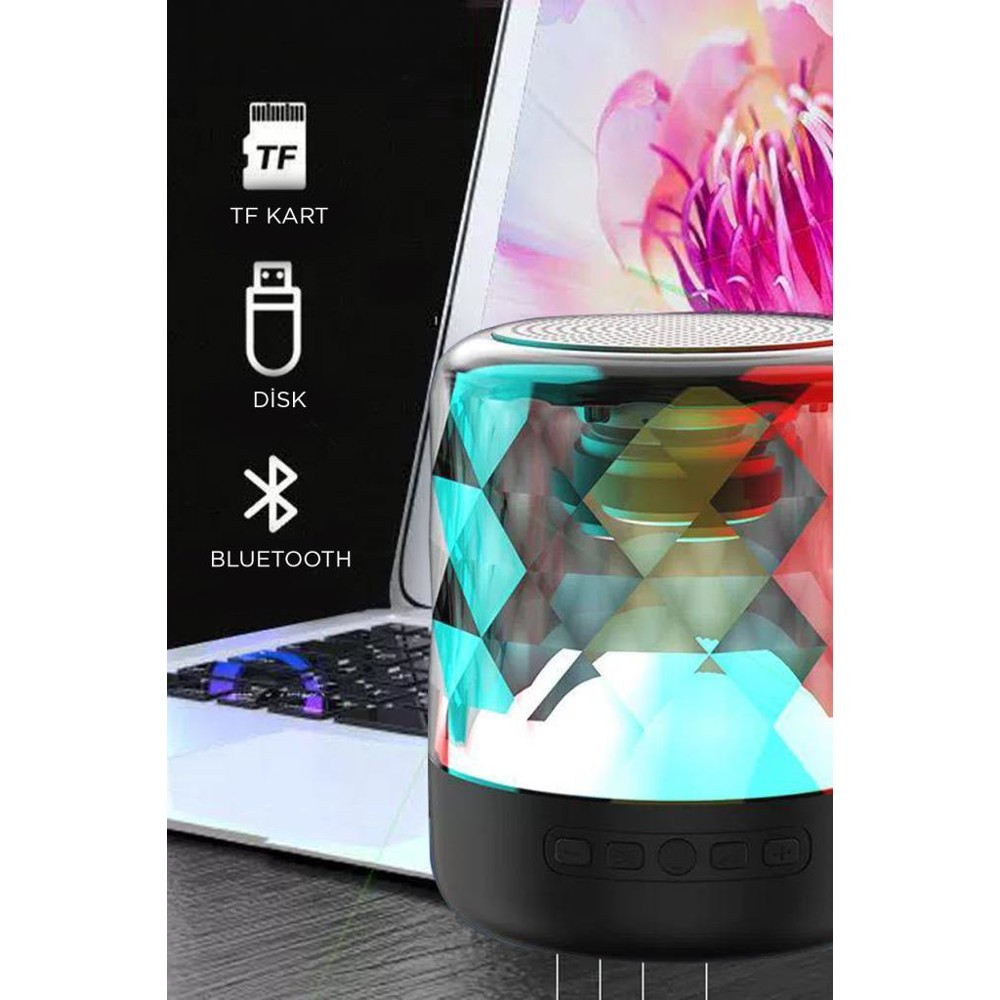 Geometrik tasarımlı, parlayan bir hoparlör bir dizüstü bilgisayarın yanında. TF kartı, disk ve Bluetooth simgeleri görülebilir.
