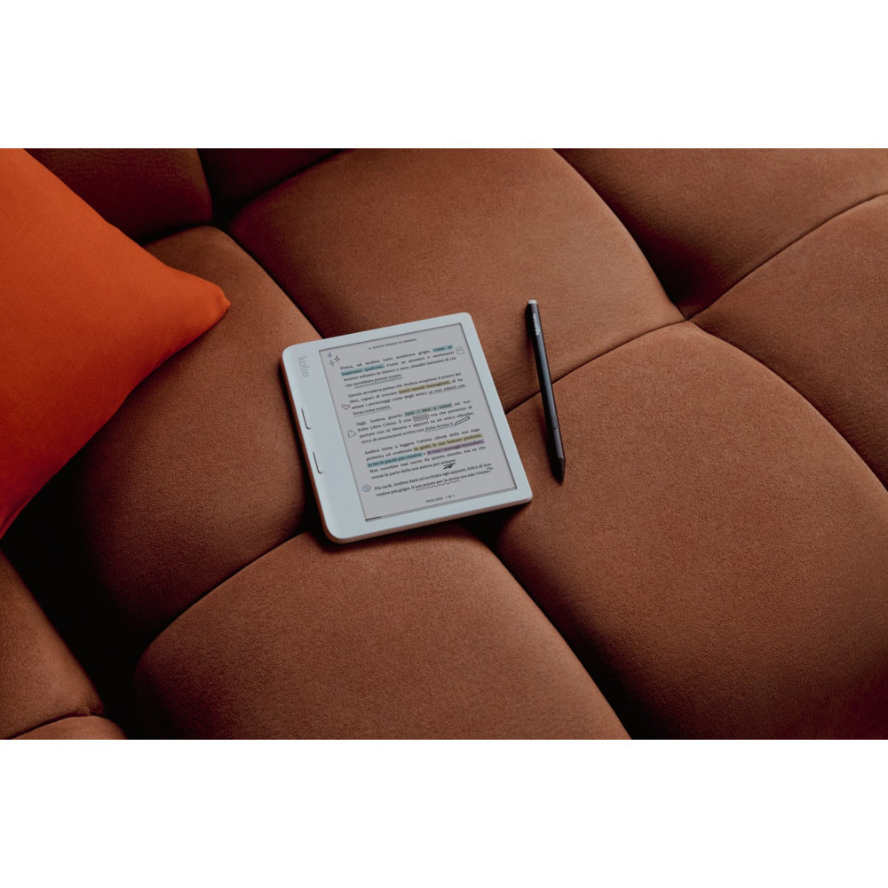 Czytnik e-booków i rysik spoczywają na brązowej sofie, w pobliżu pomarańczowej poduszki. Czytnik wyświetla tekst.