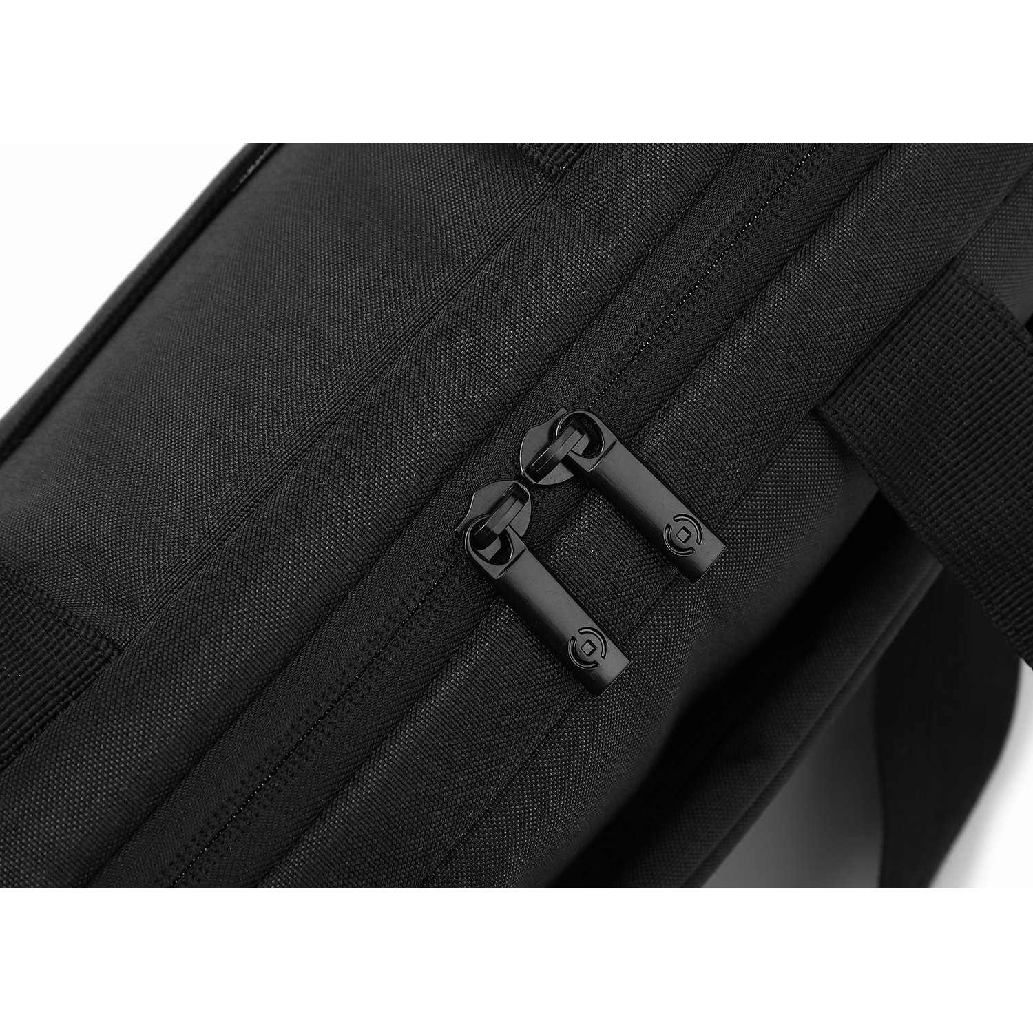 Nahaufnahme einer schwarzen Tasche. Zwei Reißverschlüsse mit schwarzen Ziehern sind sichtbar. Die Tasche hat eine strukturierte Oberfläche.