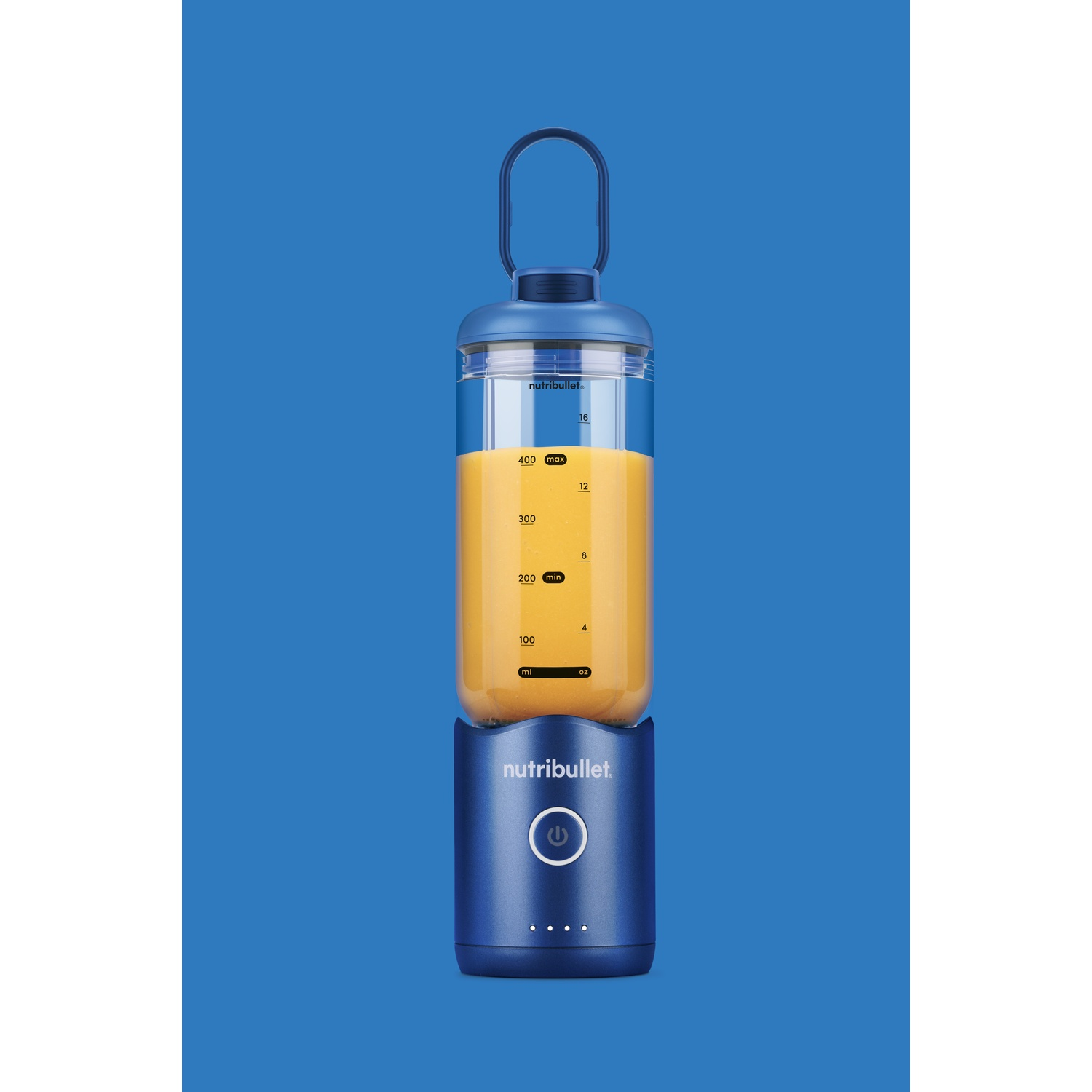 Ein blauer Nutribullet-Blender mit orangefarbener Flüssigkeit. Er hat einen Griff und einen Einschaltknopf. Der Hintergrund ist blau.