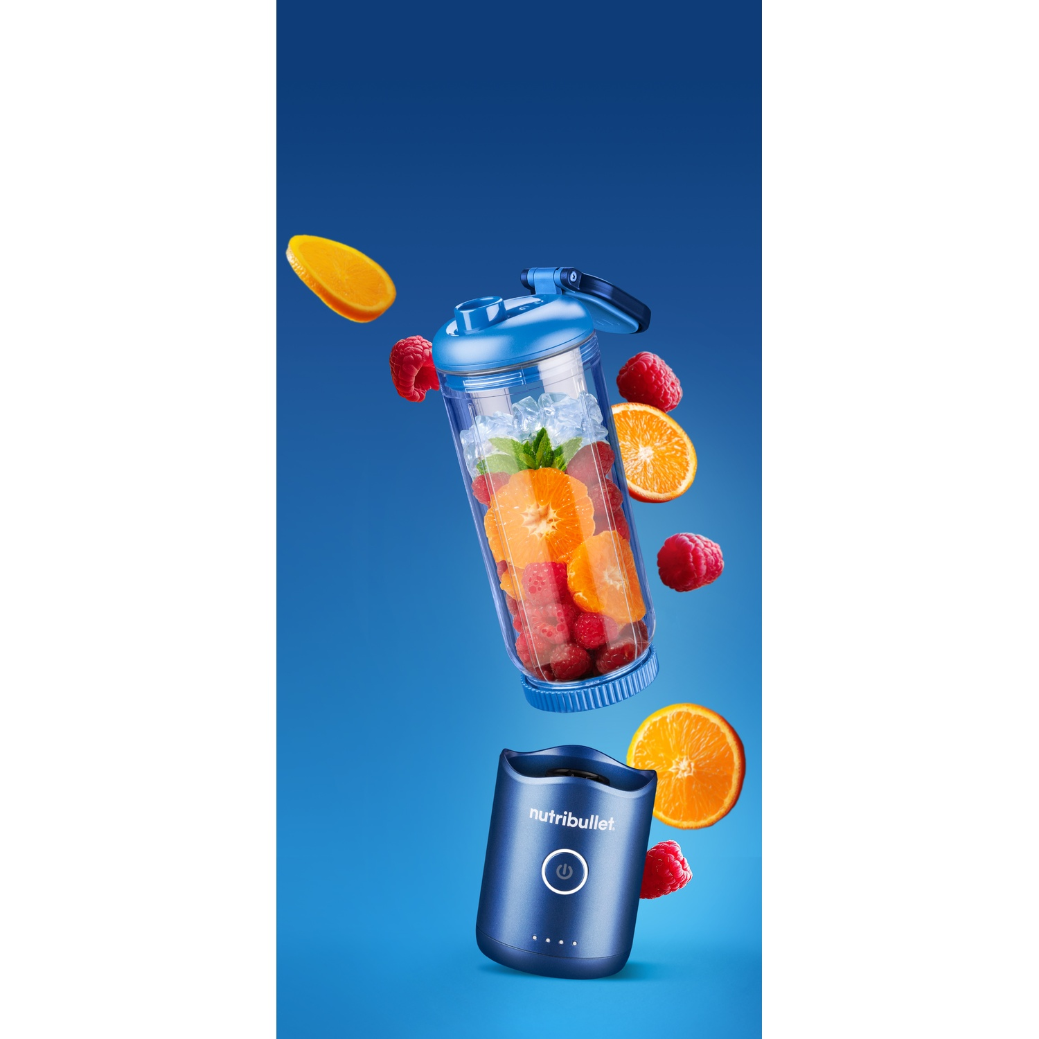 Ein blauer Nutribullet-Mixer mit Früchten darin und darum, darunter Orangen und Himbeeren, vor blauem Hintergrund.