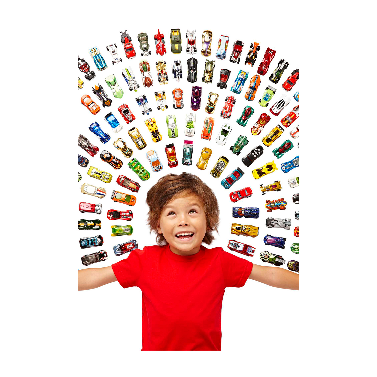 Chłopiec w czerwonej koszulce patrzy w górę na kolekcję zabawek samochodowych ułożonych w łuk nad nim.