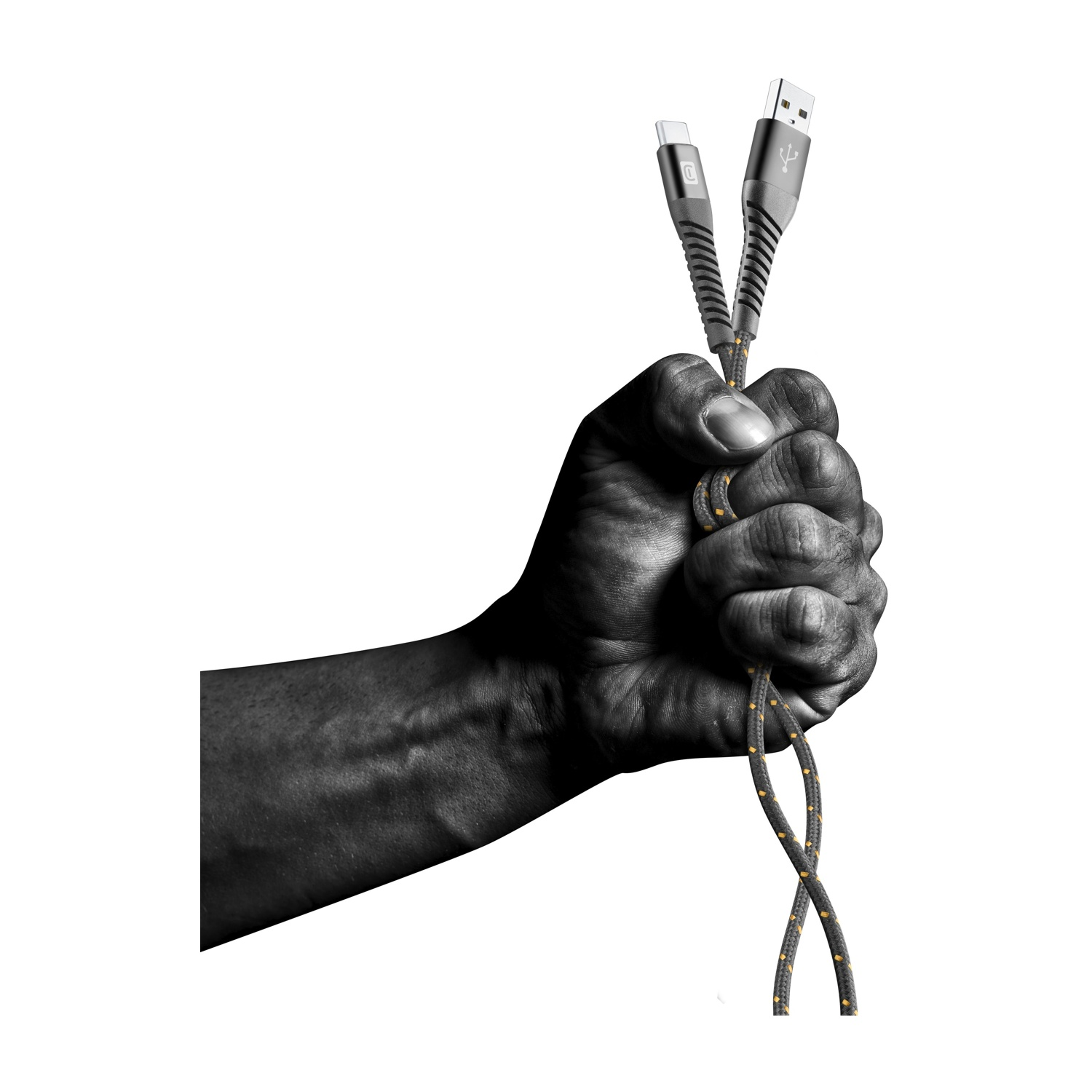 Una mano aprieta dos cables de carga. Uno USB-C, uno USB. Los cables son negros y dorados. El fondo es blanco.