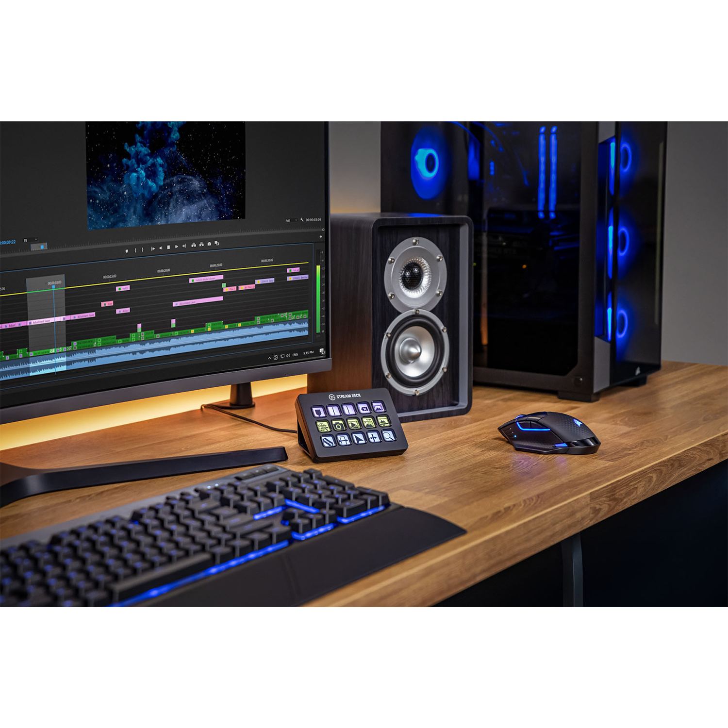 Konfiguracja biurka z monitorem wyświetlającym oprogramowanie do edycji wideo, klawiaturą, myszą, głośnikiem i komputerem z niebieskimi światłami.