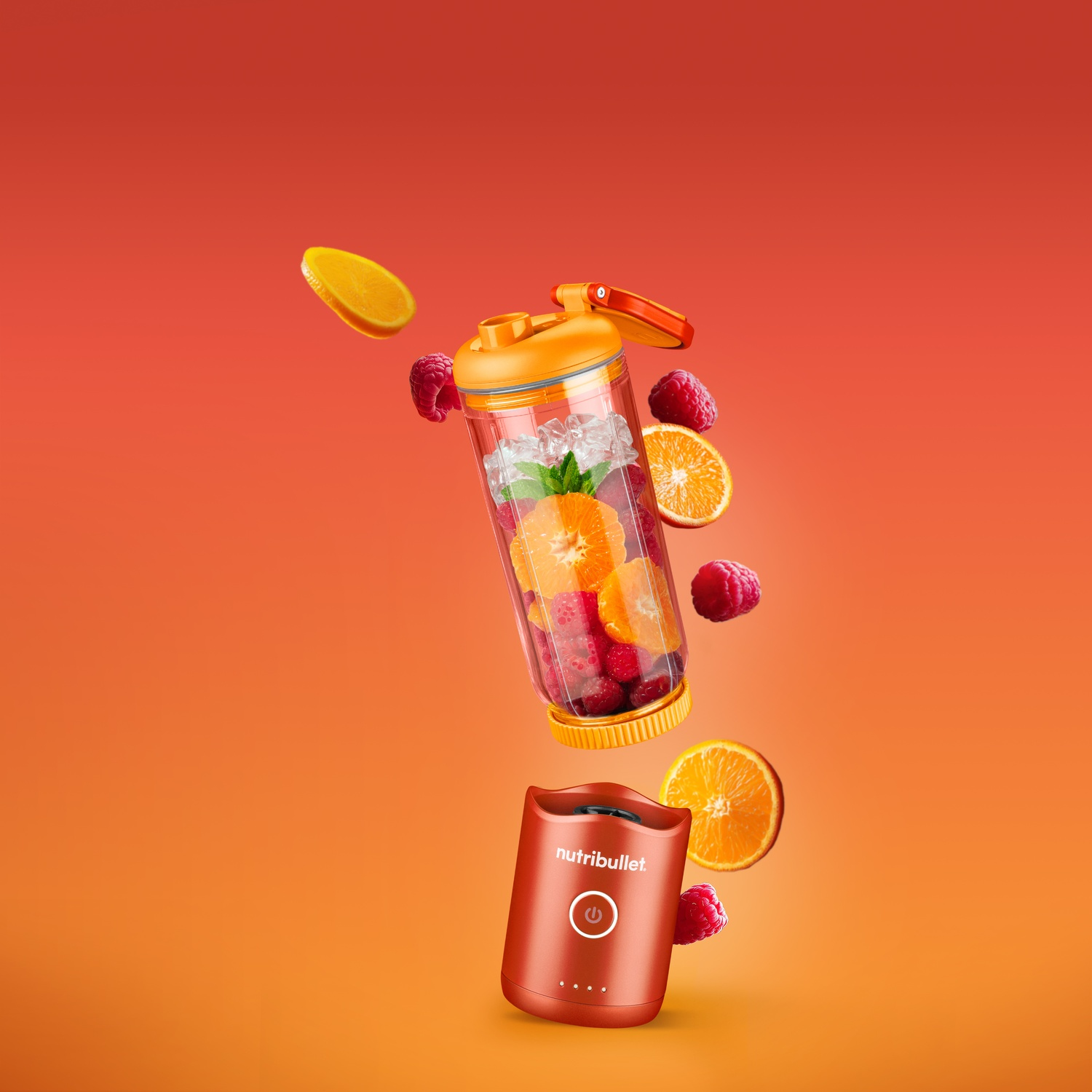 Ein Mixer mit Früchten: Orangenscheiben, Himbeeren und Eis. Der Nutribullet-Mixer ist orangefarben, mit einem Ein- und Ausschalter.