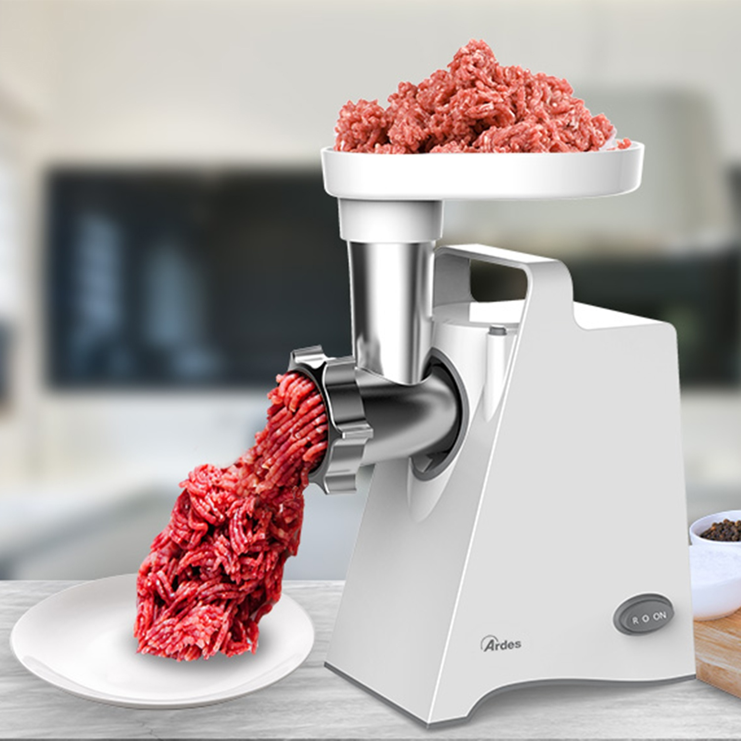 Una picadora de carne blanca está procesando carne roja. La carne picada se vierte en un plato blanco. Más carne está en la bandeja de la picadora.
