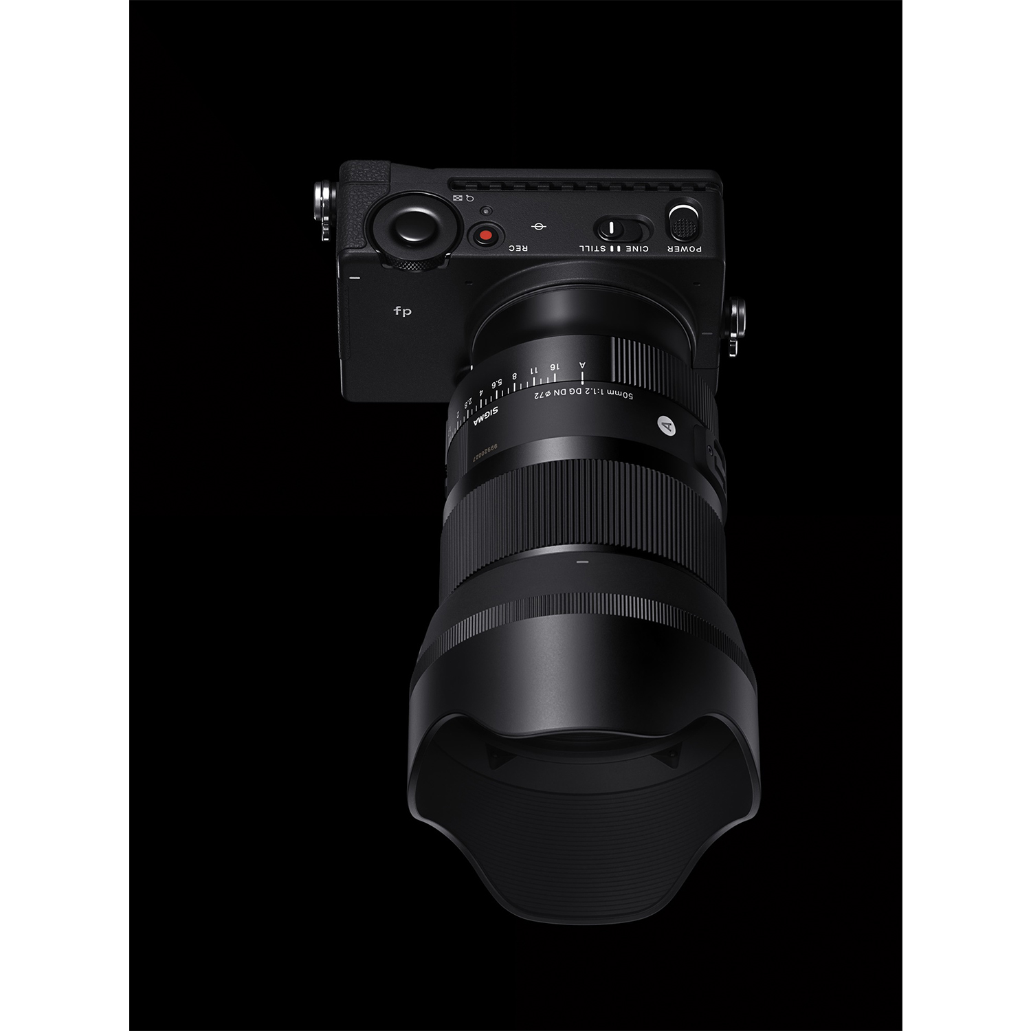 Una fotocamera Sigma fp nera con un obiettivo, su sfondo nero. Il paraluce è prominente.