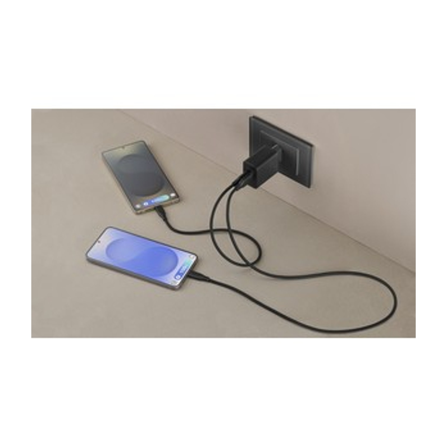 Dos teléfonos inteligentes cargando. Uno está conectado por cable, el otro ya se está cargando. Cargador negro en un enchufe de pared.