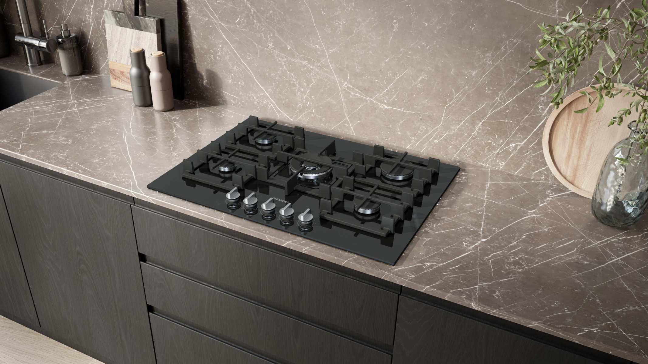 Una cucina moderna con piano cottura nero, piano di lavoro in marmo e mobili in legno scuro. Sono presenti anche oggetti decorativi.