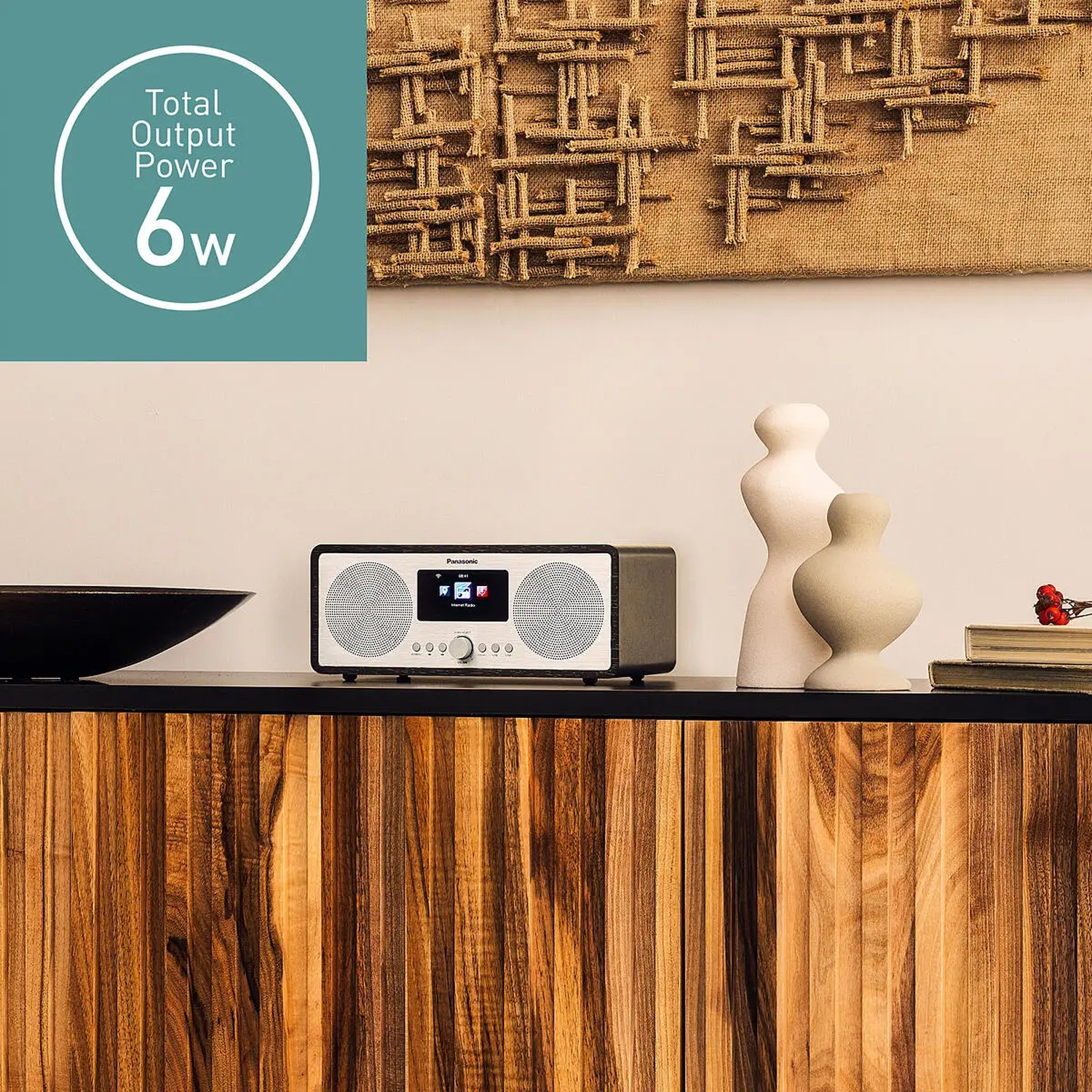 Une radio Panasonic sur une armoire en bois, avec des vases et une œuvre d'art décorative en arrière-plan. Puissance totale 6W.