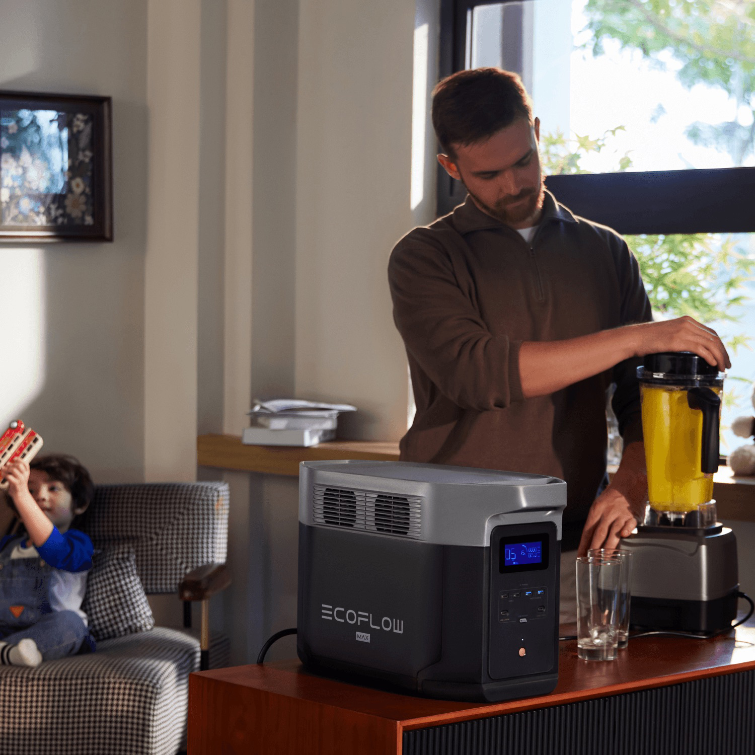 Ein Mann macht einen Smoothie, während ein Kind mit einem Spielzeug spielt. Ein Ecoflow Max steht auf einem Tisch. Fenster sind im Hintergrund.