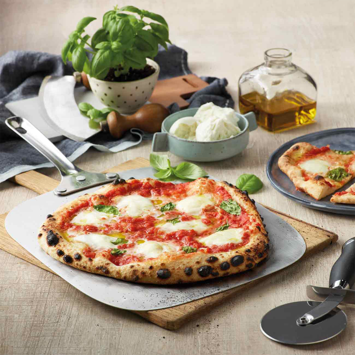 Una pizza con mozzarella, salsa di pomodoro e basilico su un tagliere di legno. Anche altri ingredienti sono esposti sul tavolo.