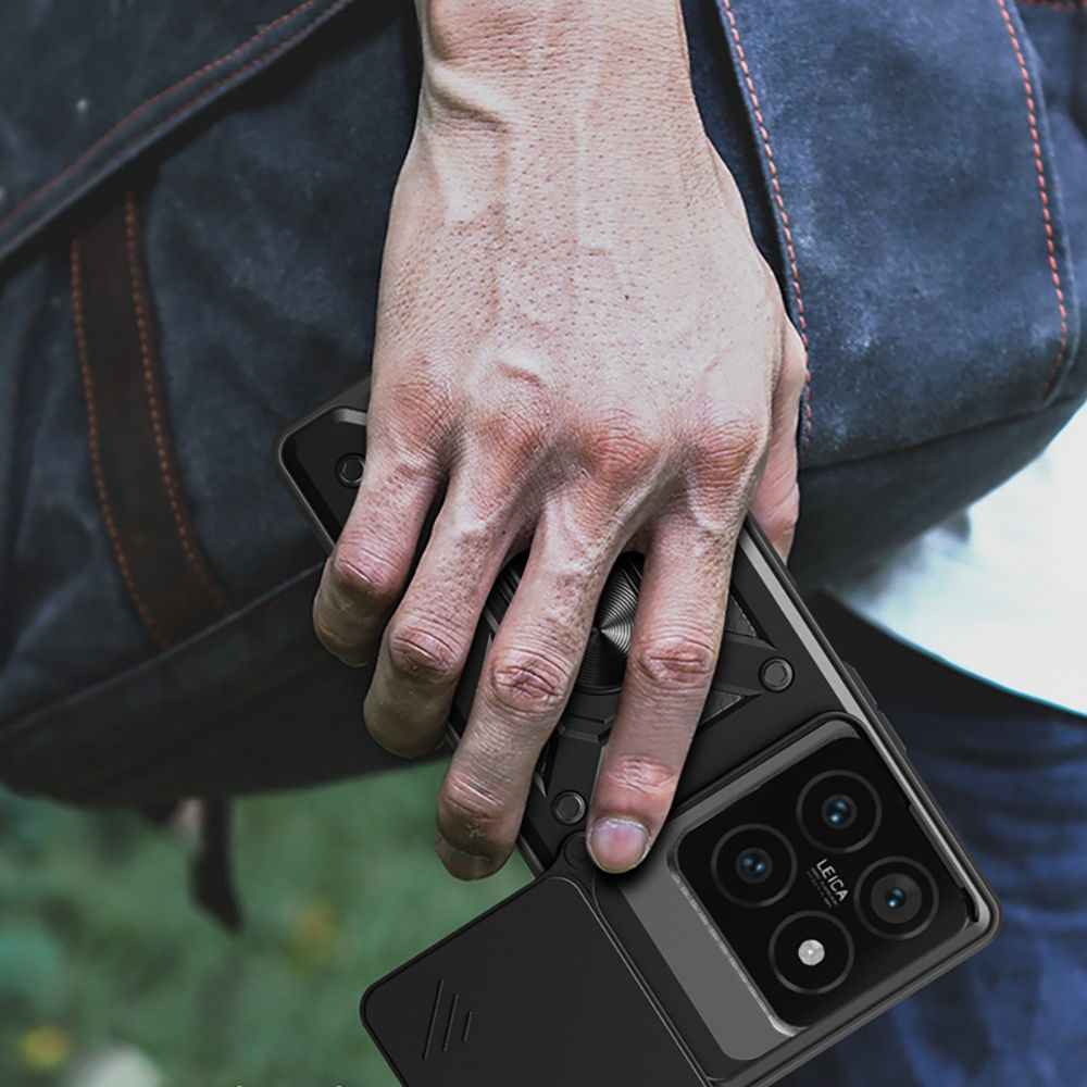 Eine Hand, die ein schwarzes Smartphone mit einer Kamerahülle hält. Ein verschwommener Rucksack ist im Hintergrund. Das Telefon hat Leica-Markenzeichen.