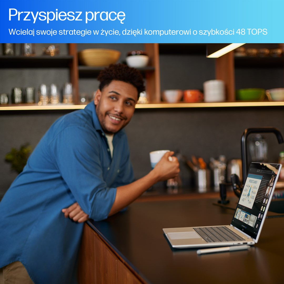 Mężczyzna uśmiecha się opierając o blat z laptopem. Trzyma kubek. Na laptopie wyświetlana jest prezentacja.