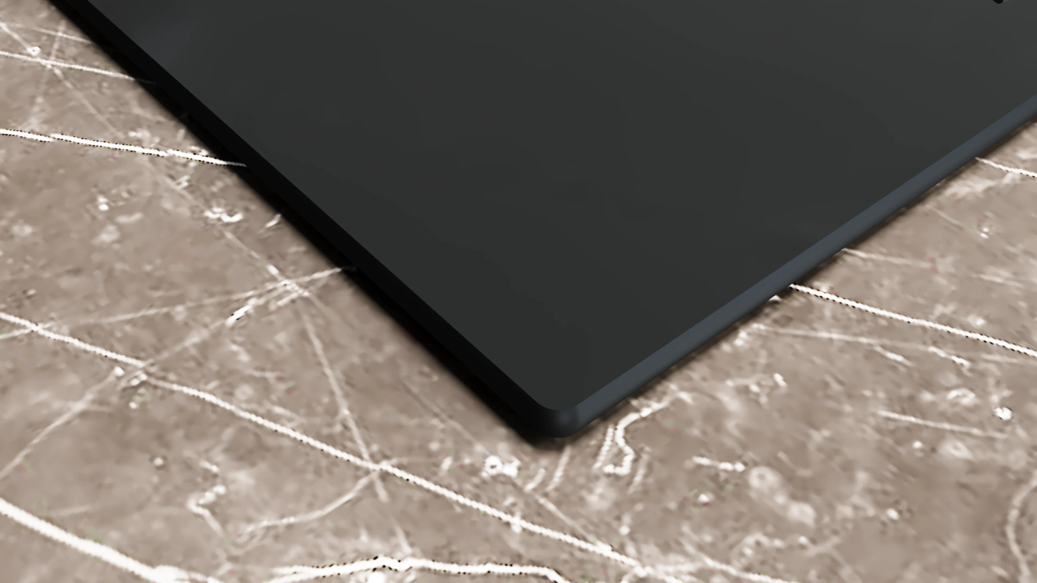 Primo piano di un laptop grigio scuro su una superficie di marmo marrone. L'angolo del laptop è visibile.